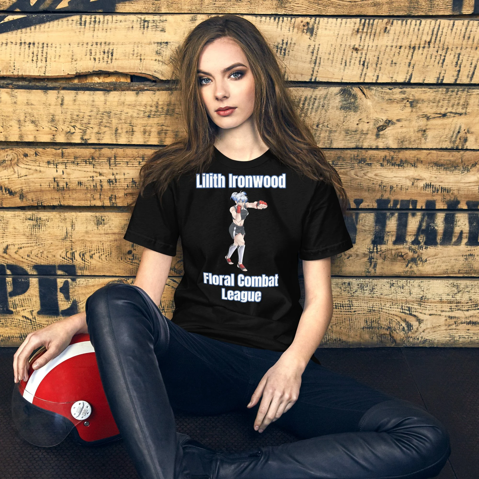 A young woman with long, wavy brown hair and blue eyes sitting against a wooden wall. She is wearing a black t-shirt with cartoon characters and text on it, along with black leather pants. She is holding a vintage-style red and white vinyl record player and has a serious expression.