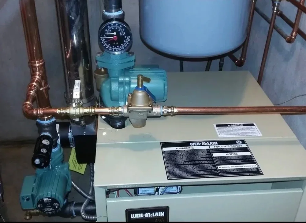 A Weil-Mclain boiler system with copper pipes, gauges, and pumps.