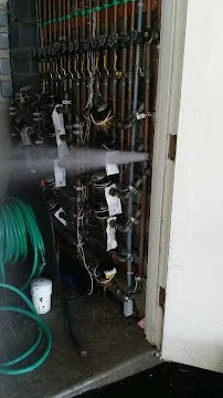 A plumbing system with pipes, valves, and hoses in a utility closet.