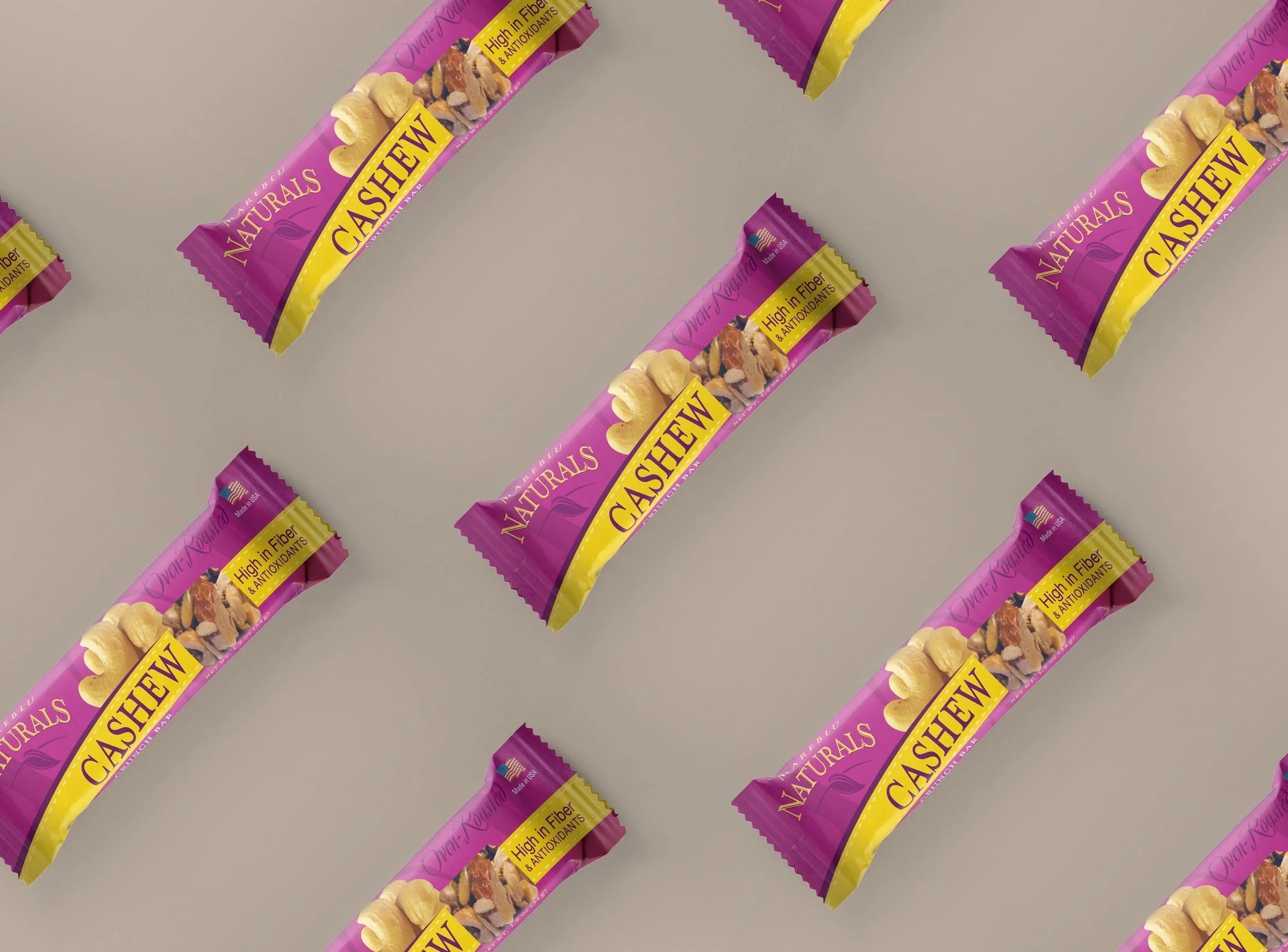 Multiple cashew snack bars with purple and yellow packaging, arranged on a light gray surface.