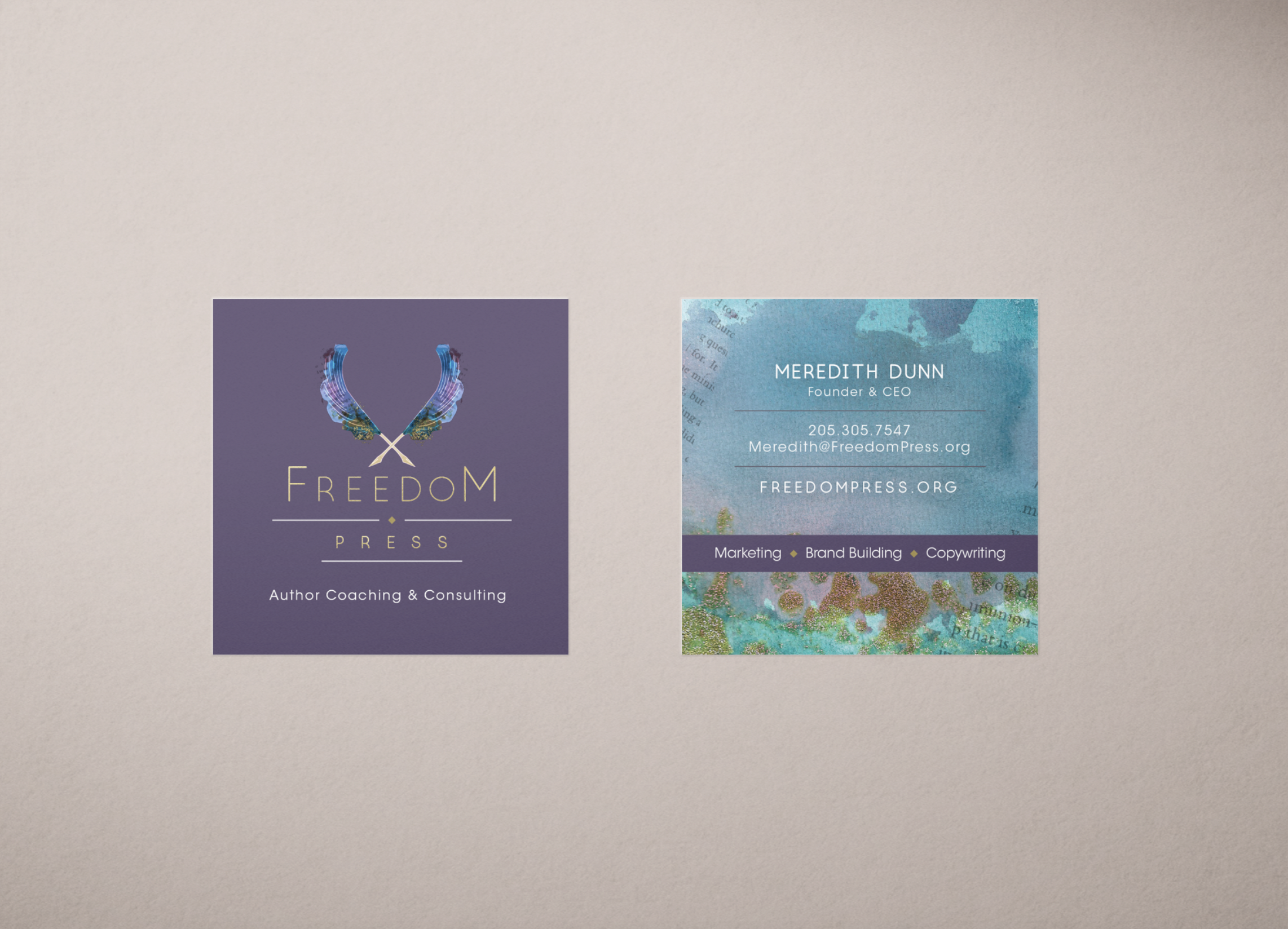 Two business cards on a beige background. The left card is purple with a butterfly logo and text for Freedom Press, author coaching, and consulting. The right card is blue with contact information for Meredith Dunn, including her email, phone number,