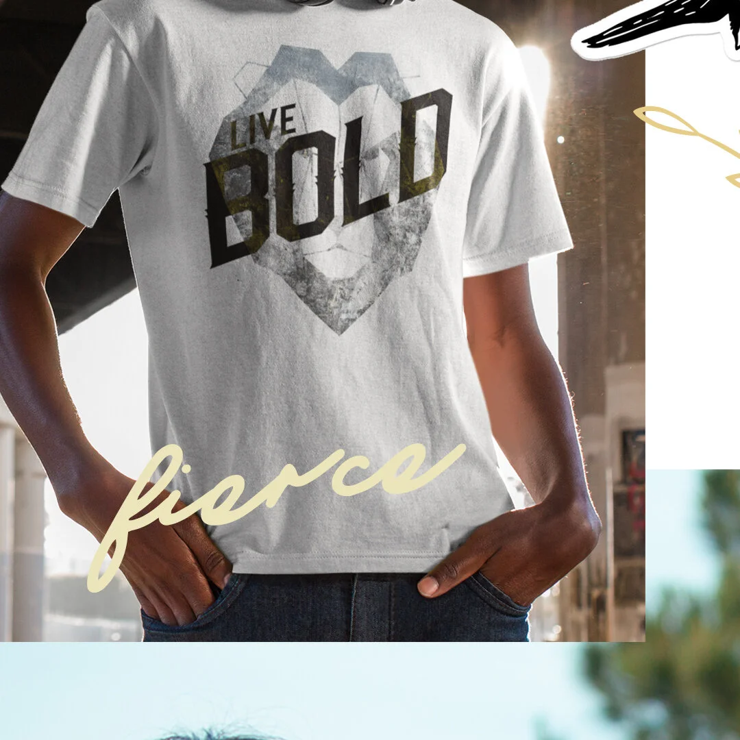 Person wearing a white T-shirt with the phrase 'Live Bold' inside a heart design. The image has a light background with natural lighting.
