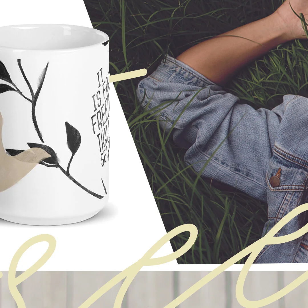 Close-up of a white ceramic mug with black leaf design and text, resting on a white surface next to a person lying on grass, wearing blue denim shorts.