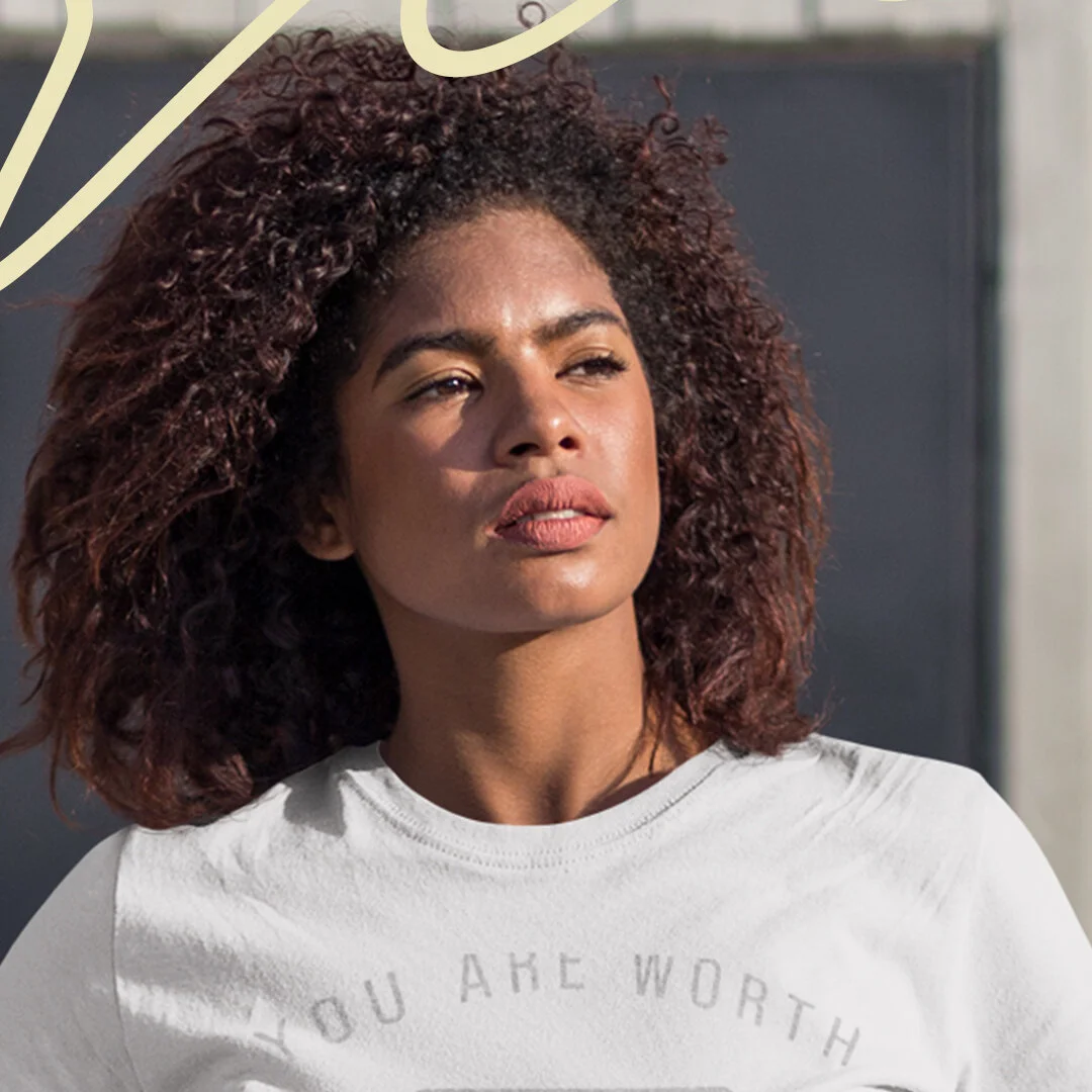 A woman with curly hair wearing a white shirt looking off into the distance.