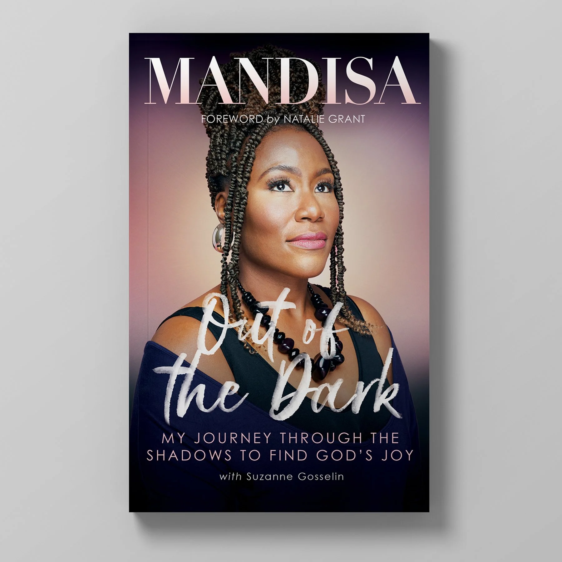 Book cover titled 'Out of the Dark' by Mandisa, with a foreword by Natalie Grant, featuring a portrait of a woman with braided hair, wearing a necklace and earrings, against a soft gradient background.