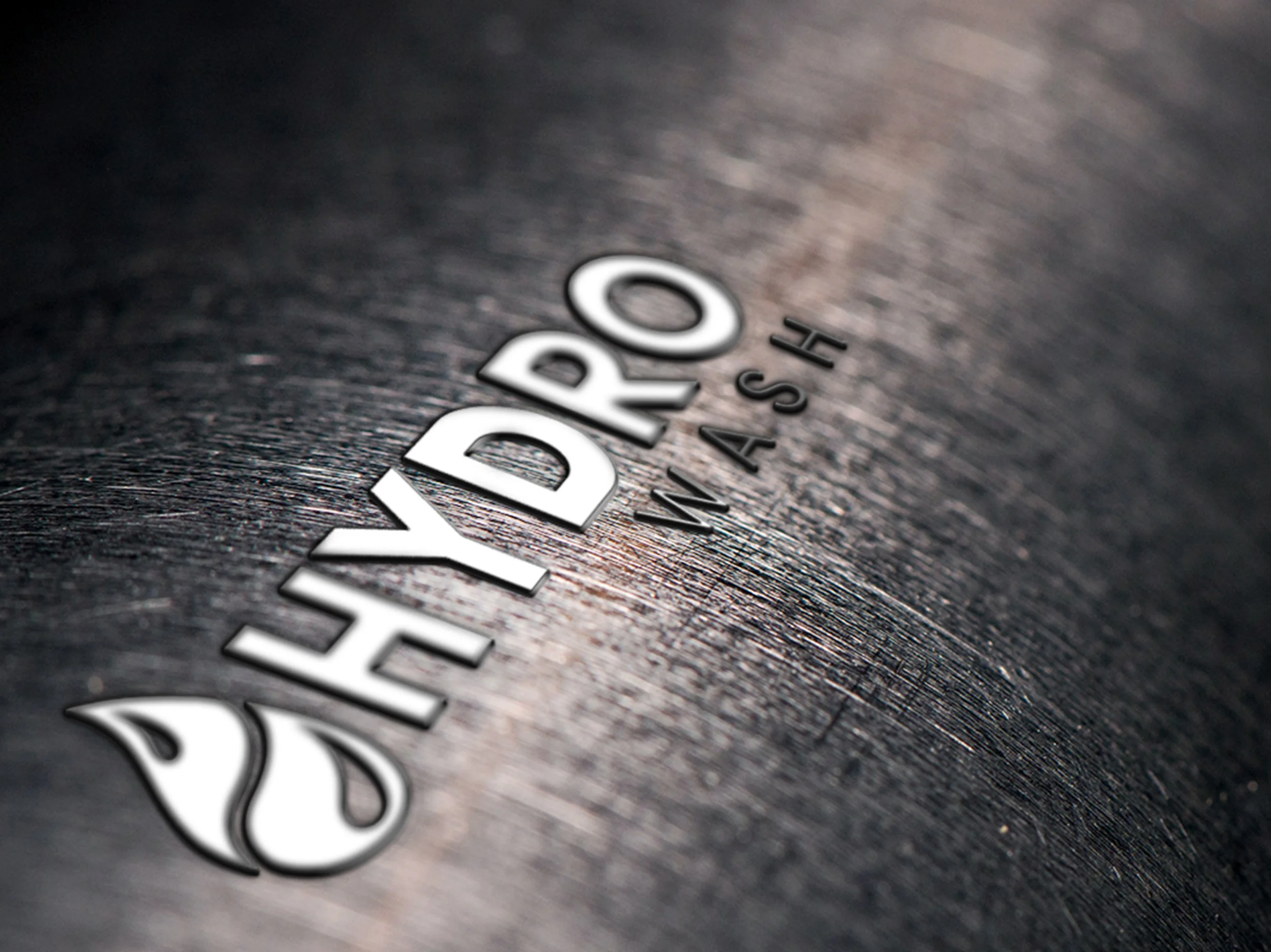 Close-up of the men's watch brand HYDRO WASH with silver lettering on a textured dark surface.