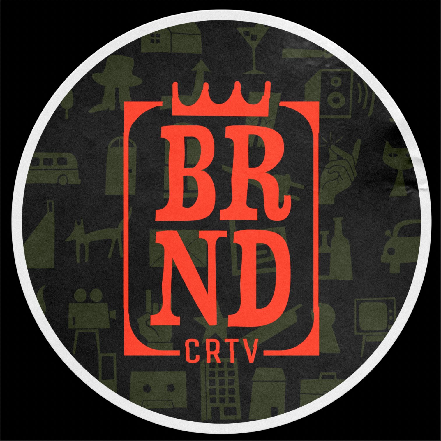 A circular logo with a black background and a white border. Inside, the logo has a stylized crown at the top, large red letters spelling 'BRND' with the 'R' and 'N' overlapping. Below, there is red text 'CRTV'. The background of the circle features v