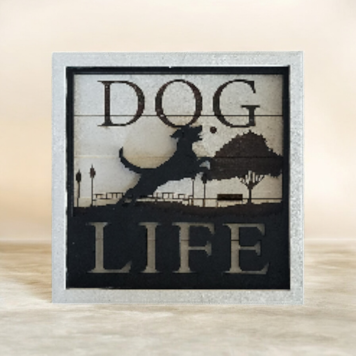 Decorative sign with silhouette of a dog jumping, trees, and mountains, with the text 'DOG LIFE'.