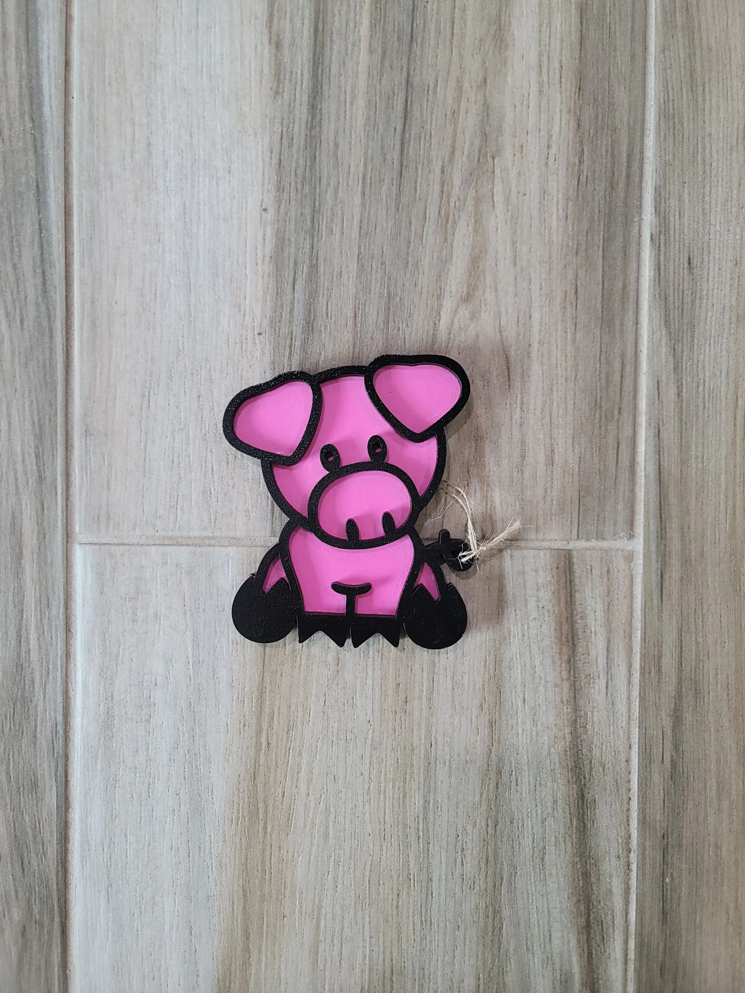 Pink pig-shaped with black outline made of wood.