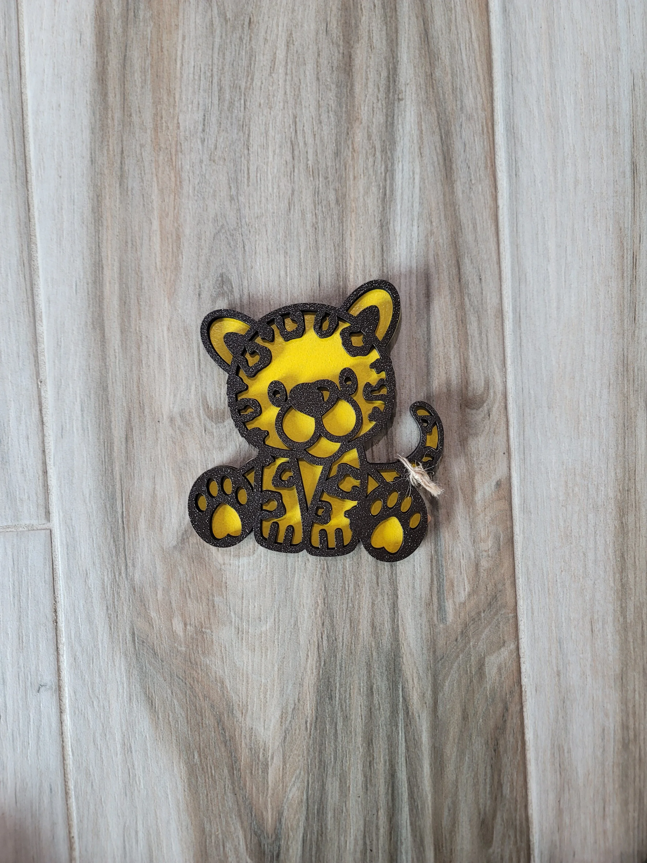 A yellow and black bear cub with cut-out details made of wood.