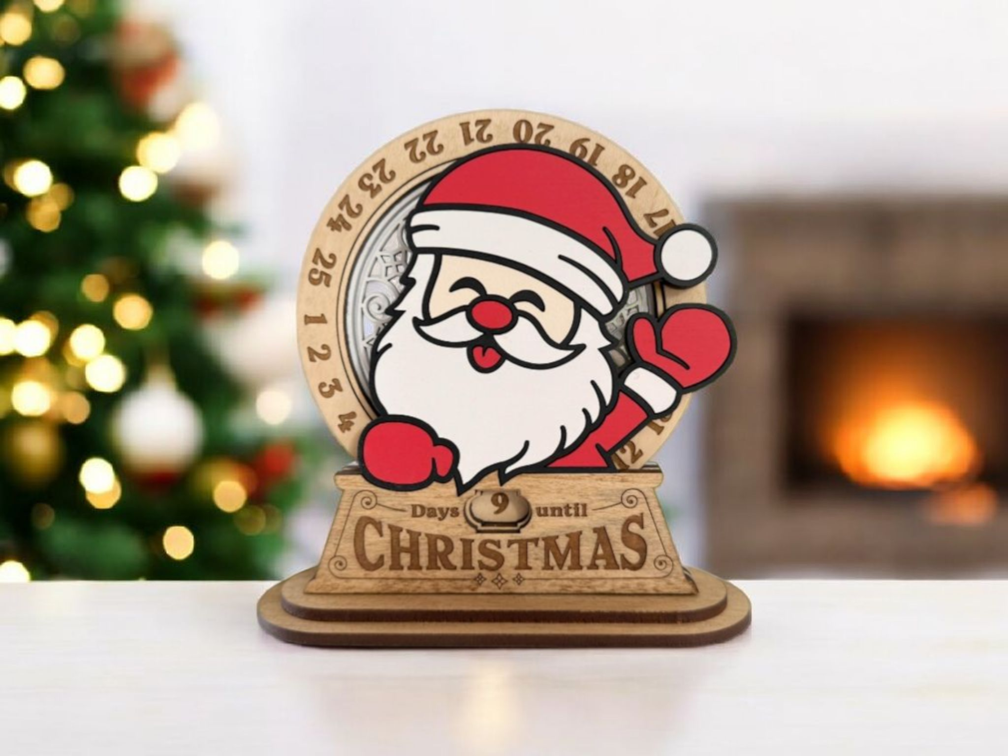 A festive countdown wooden decoration featuring Santa Claus waving, with a clock showing 9 days until Christmas, set against a blurred background of a Christmas tree and a lit fireplace.
