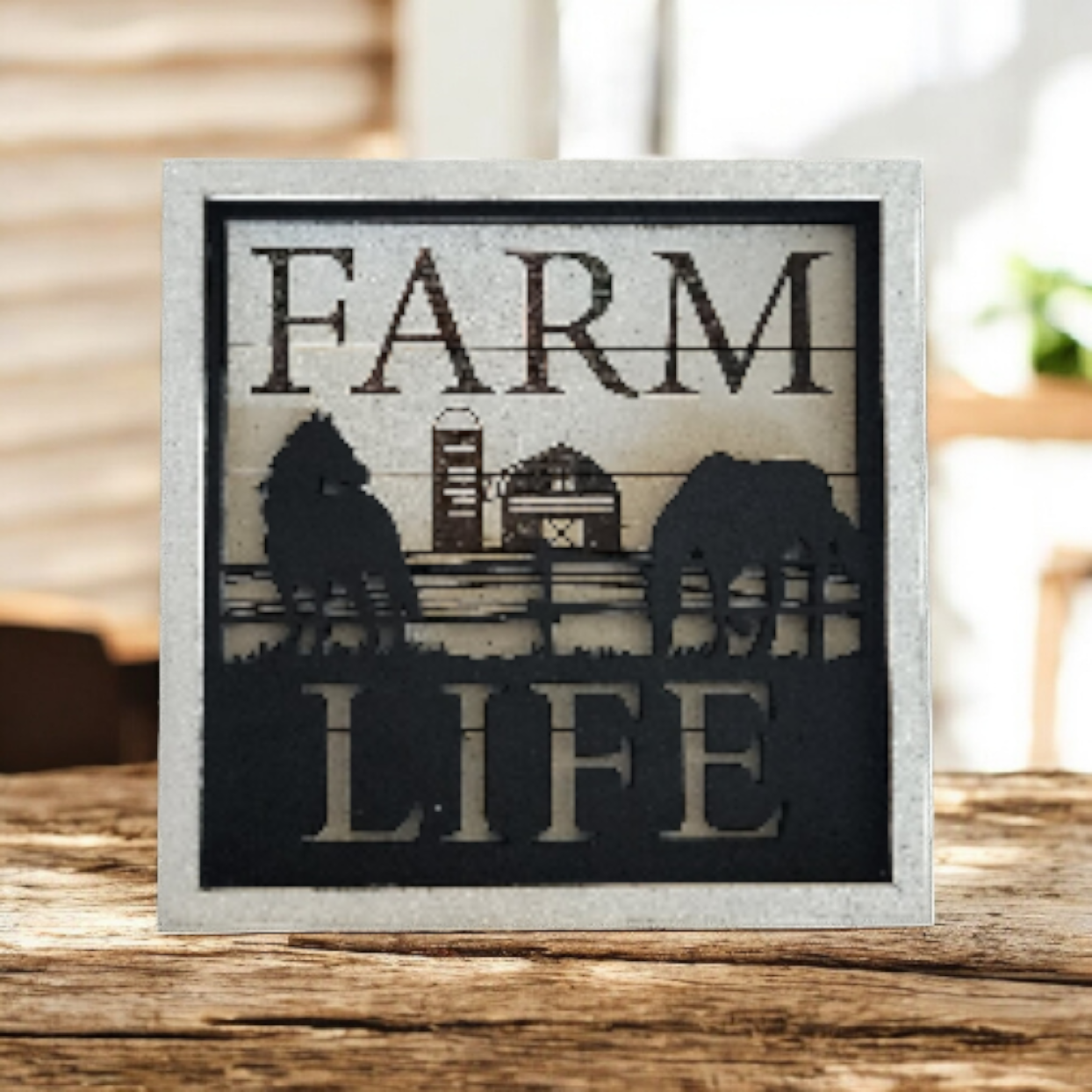 Decorative sign with the words "Farm Life" and silhouettes of a cow, barn, and silo against a farm background.