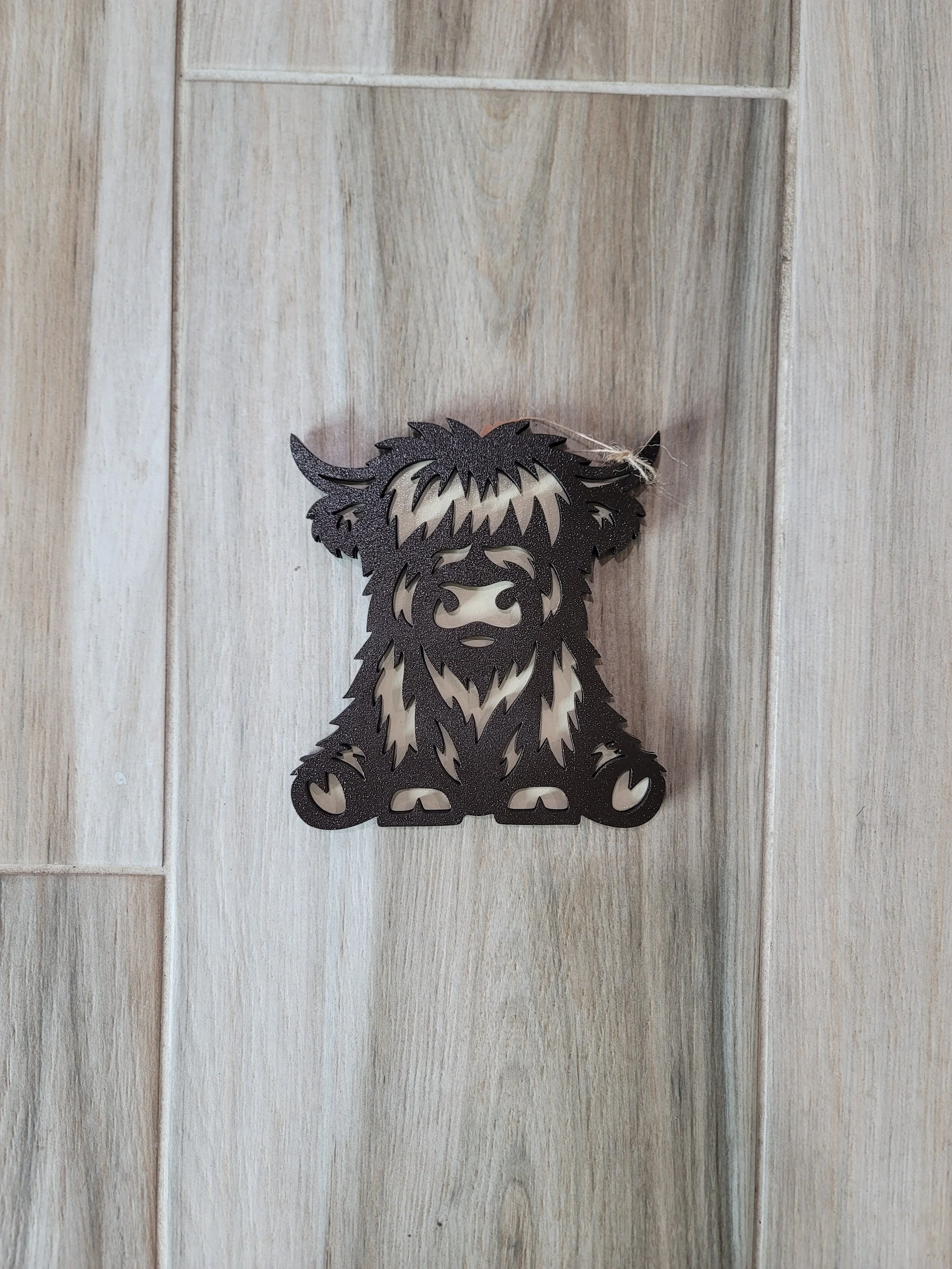 A black cutout of a Highland cow's face and front legs