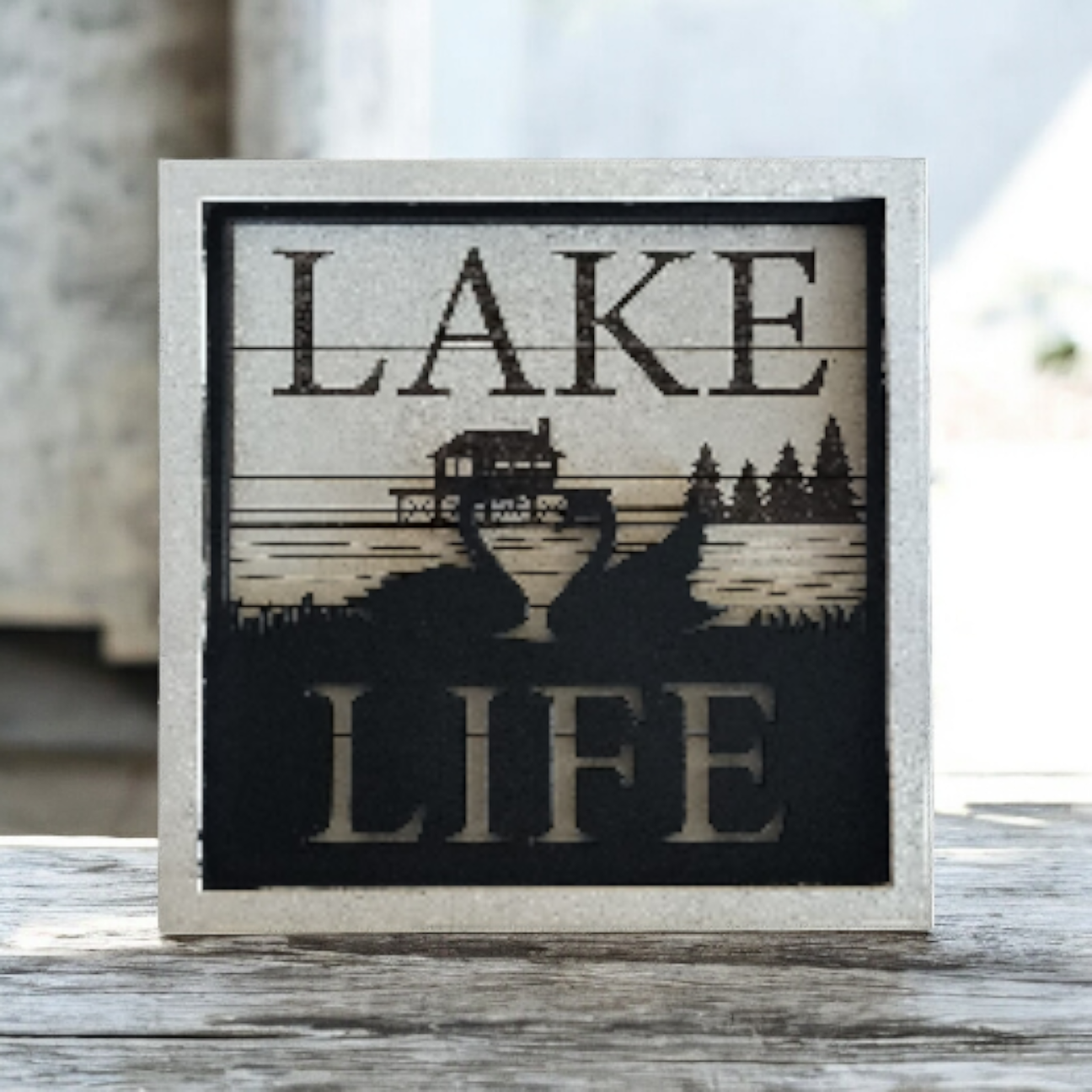 Decorative plaque with the words 'Lake Life' and a scenic illustration of a lake, trees, and a boat
