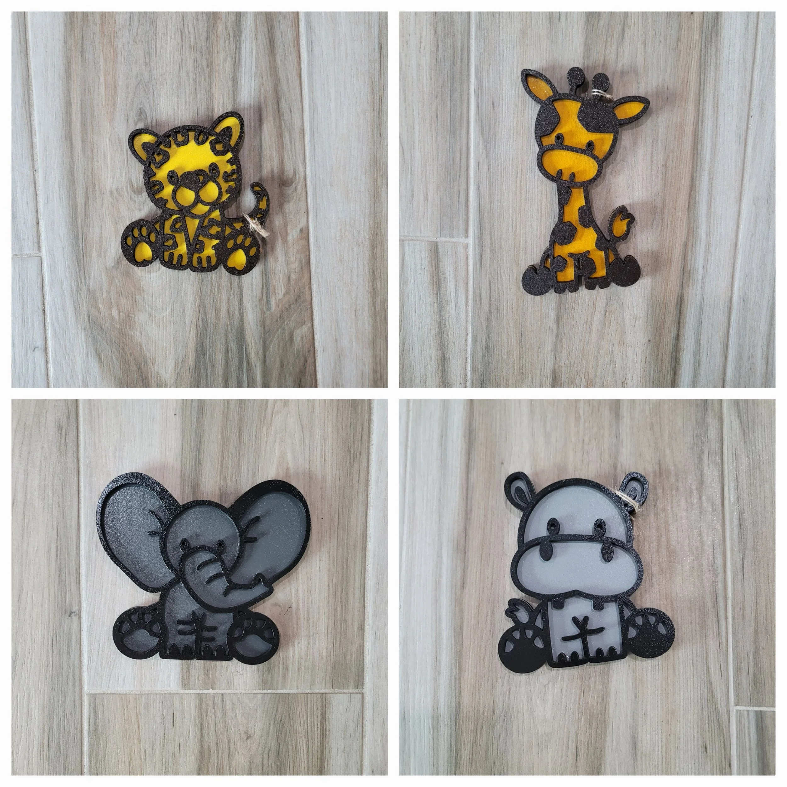 Four animal-shaped cutouts on a wooden surface: a yellow and black tiger, a yellow and black giraffe, a gray elephant, and a gray hippopotamus.