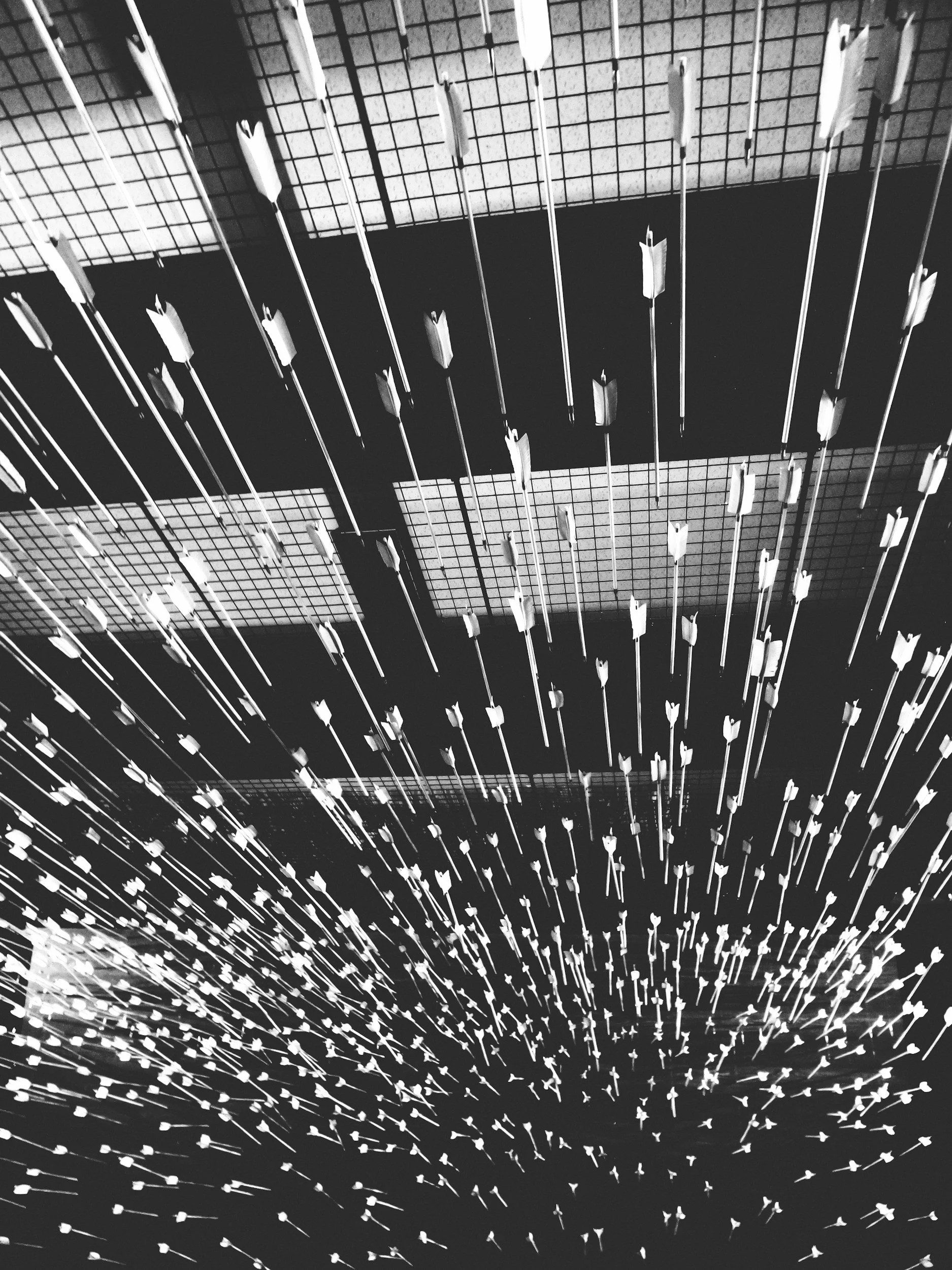 Multiple arrows or spears are suspended from above, pointing downward, in a pattern that creates a sense of motion and depth.
