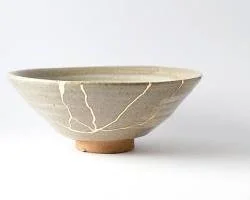 Photographie d'un bol antique restauré avec de l'or selon l'art du Kintsugi, illustrant la résilience et la réparation des liens.