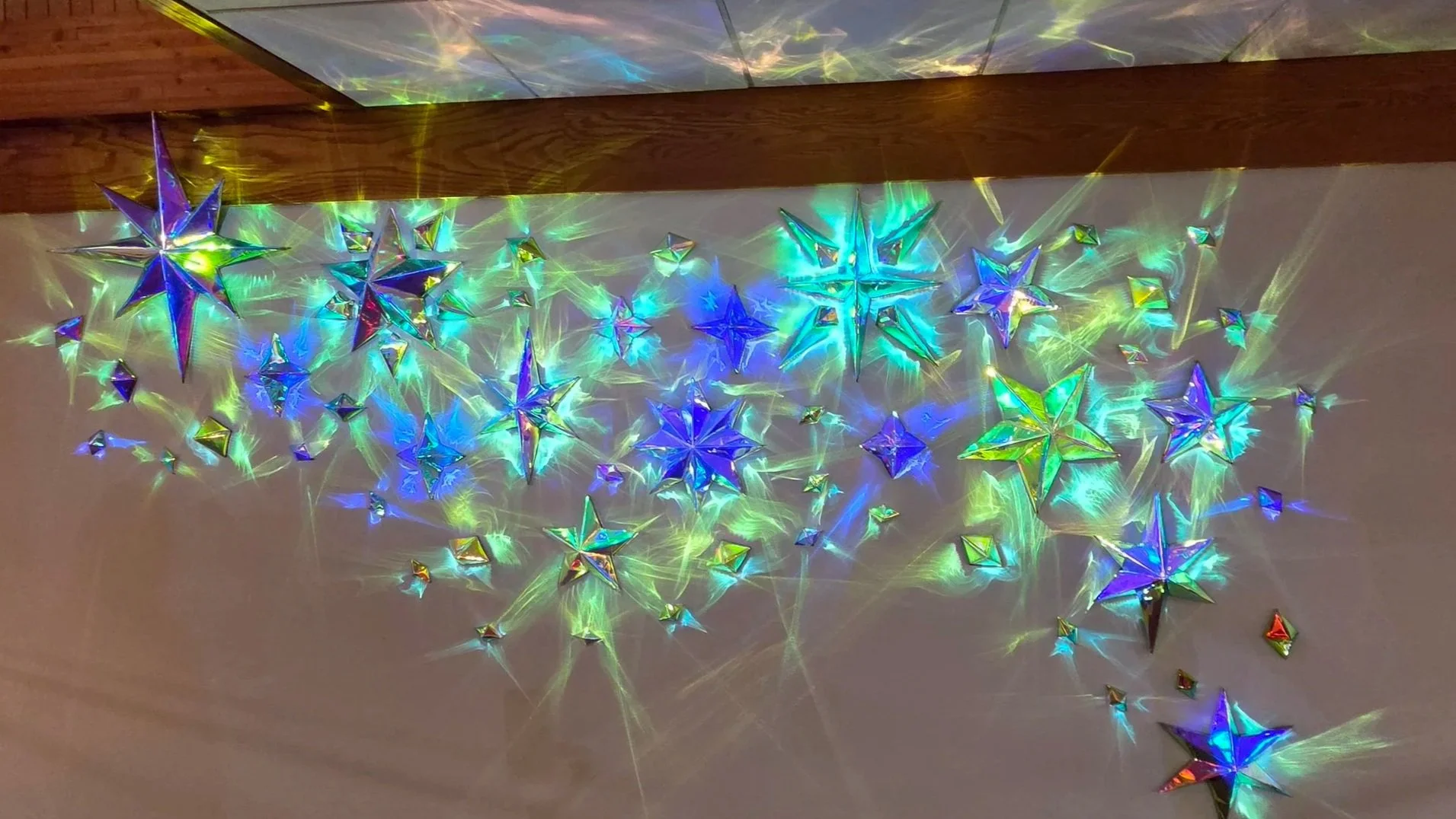 Abstract digital art with sharp, reflective, pyramid-shaped structures, swirling light patterns, and vibrant colors including green, purple, and rainbow hues.