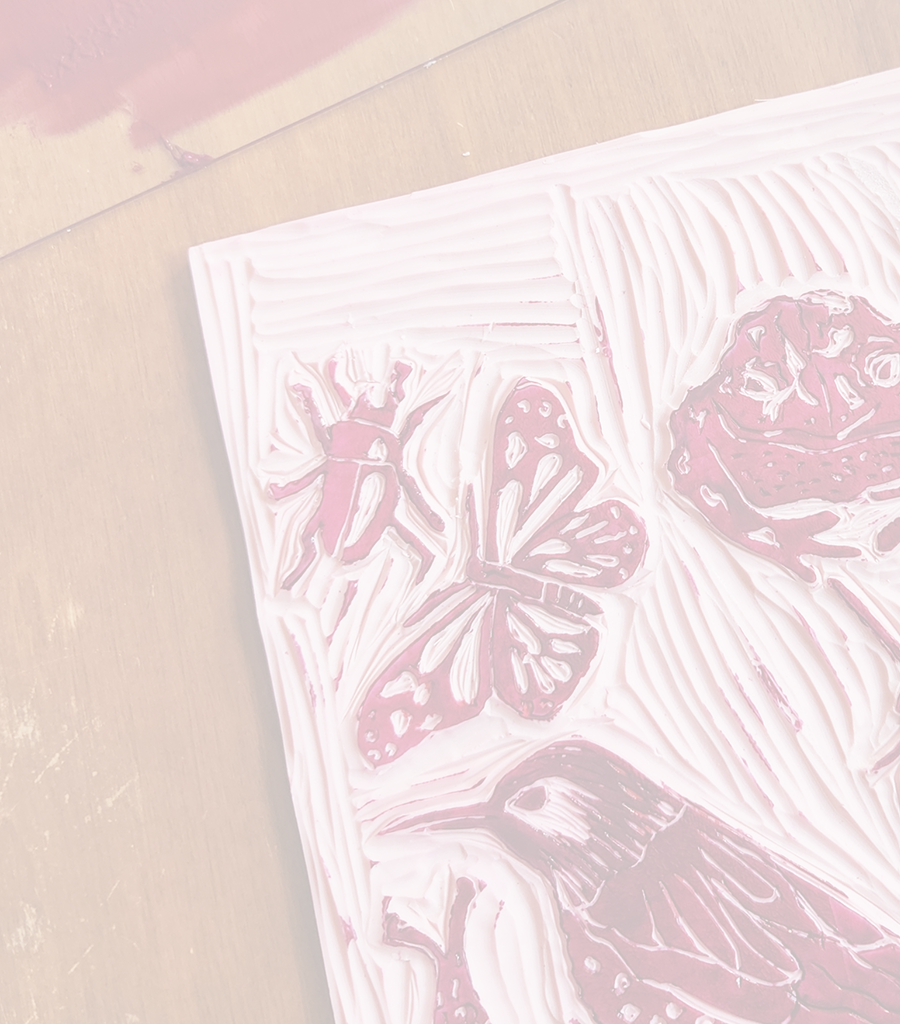Close-up of a carved block print showing insect and bird shapes in relief.