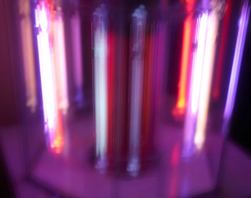 Abstract image of the neon tubes of the BioCharger with blurred vertical neon lights in purple, pink, red, and blue colors.