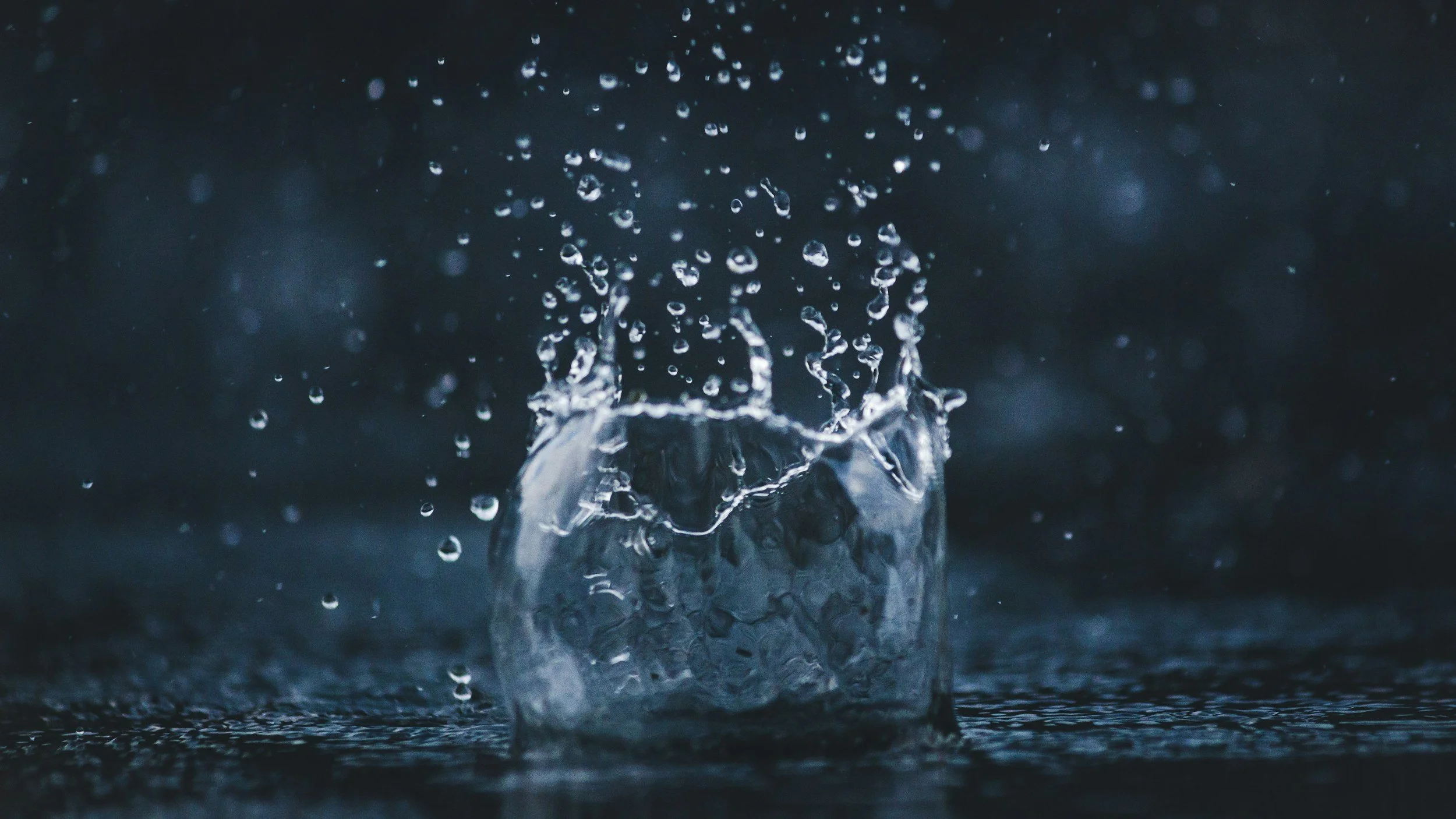 Close-up of a water splash hitting a surface in a dark setting.