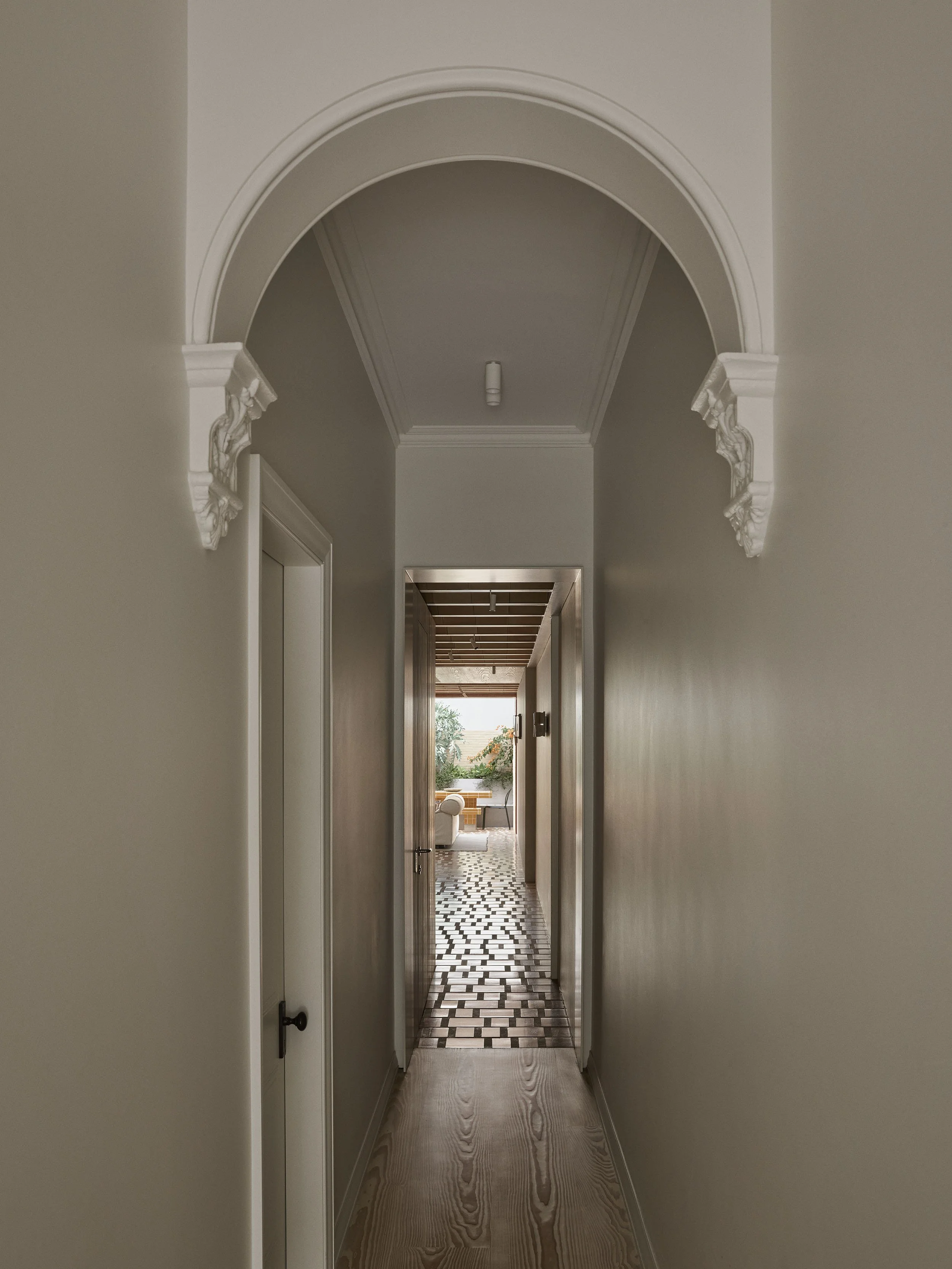 Old meets new in the front hallway. A traditional archway frames the view of a new steel portal into the extension at Clay House Sydney Heritage Restoration by Muci architects.