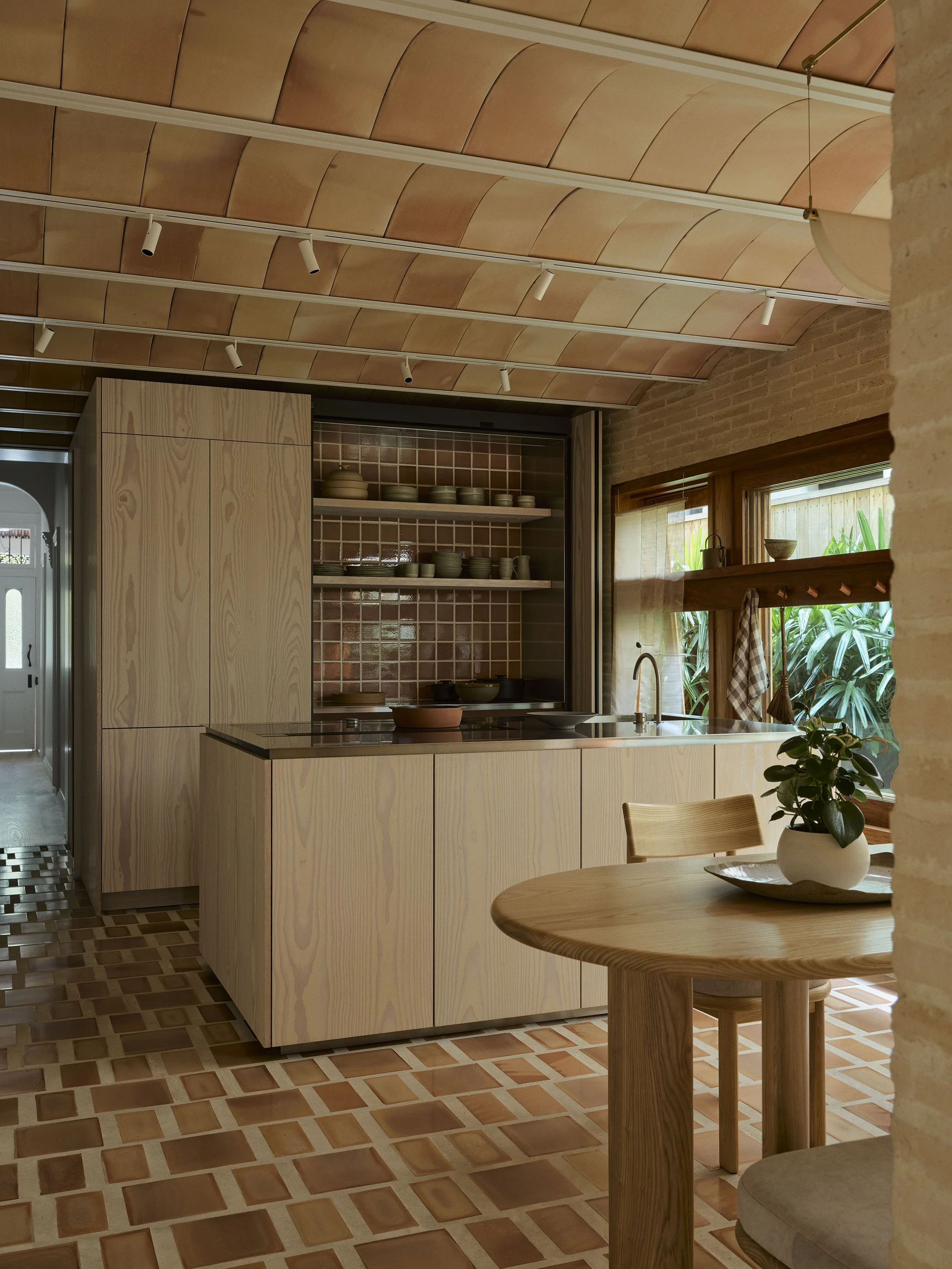 The dining room of Clay House by architects in Newcastle, Muci. A Dinesen Douglas Fir kitchen with terracotta floor and terracotta bovedilla ceiling. Flos track lighting.