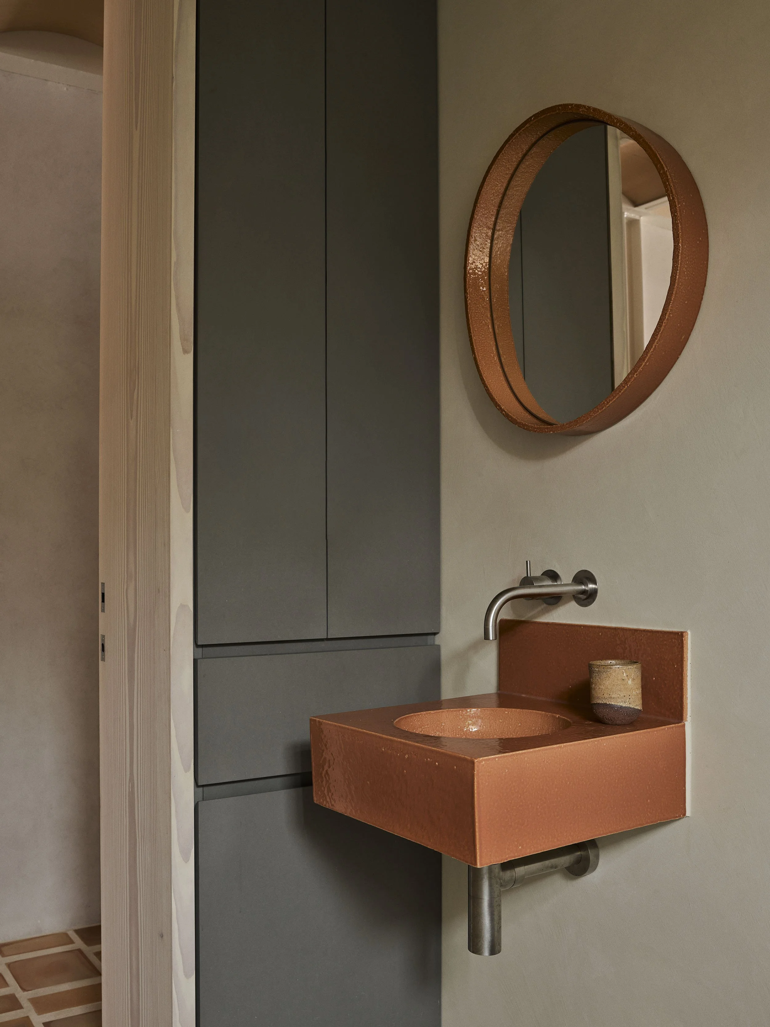 Atelier Franssens wall hung basin in orange colour with microcment bathroom wall in the Sydney terrace renovation, clay house by Muci architects.