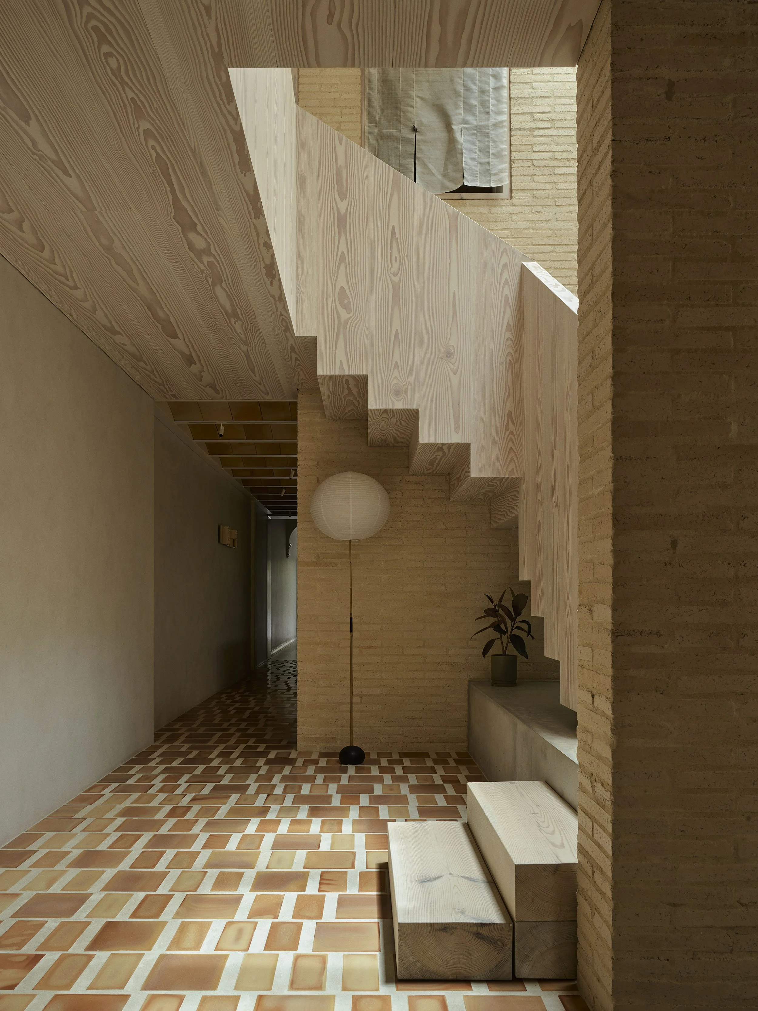 in the stairwell at clay house Sydney terrace renovation by Muci architects. Looking toward kitchen with Noguchi floor lamp, terracotta tile floor with maxi-grout plus Dinesen timber stair and bridge above.