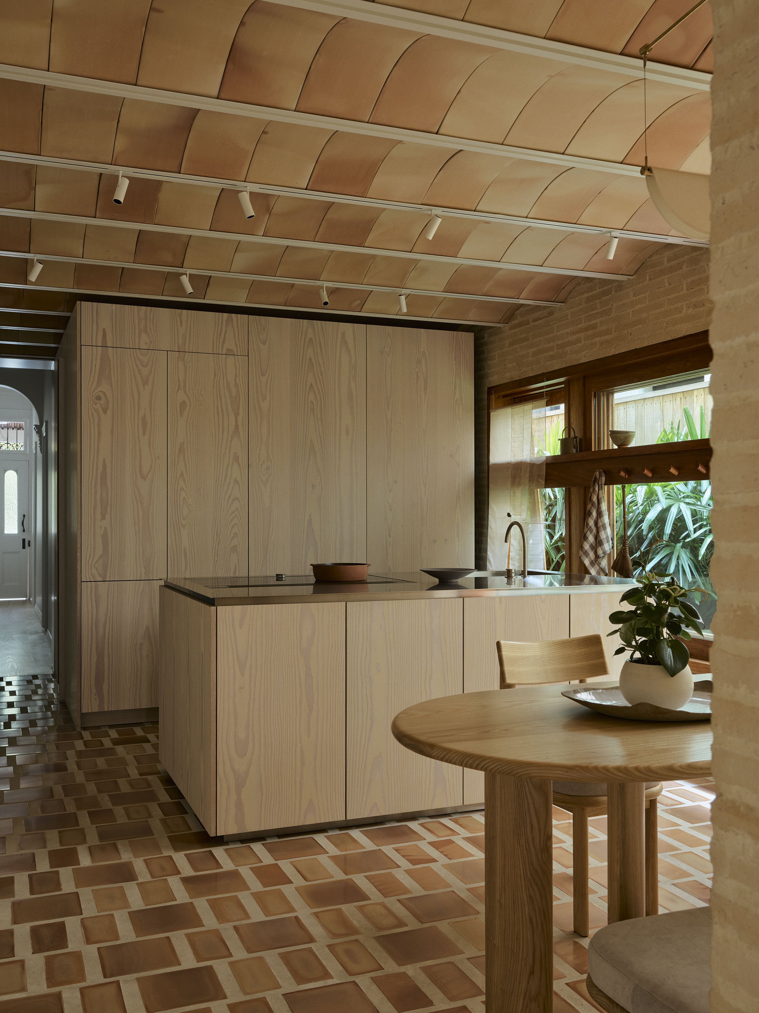 The kitchen at Clay House, the Sydney terrace renovation by Muci architects. It shows a concealed kitchen with pocket doors made in Dinesen Douglas fir. Terracotta floor and terracotta ceiling.