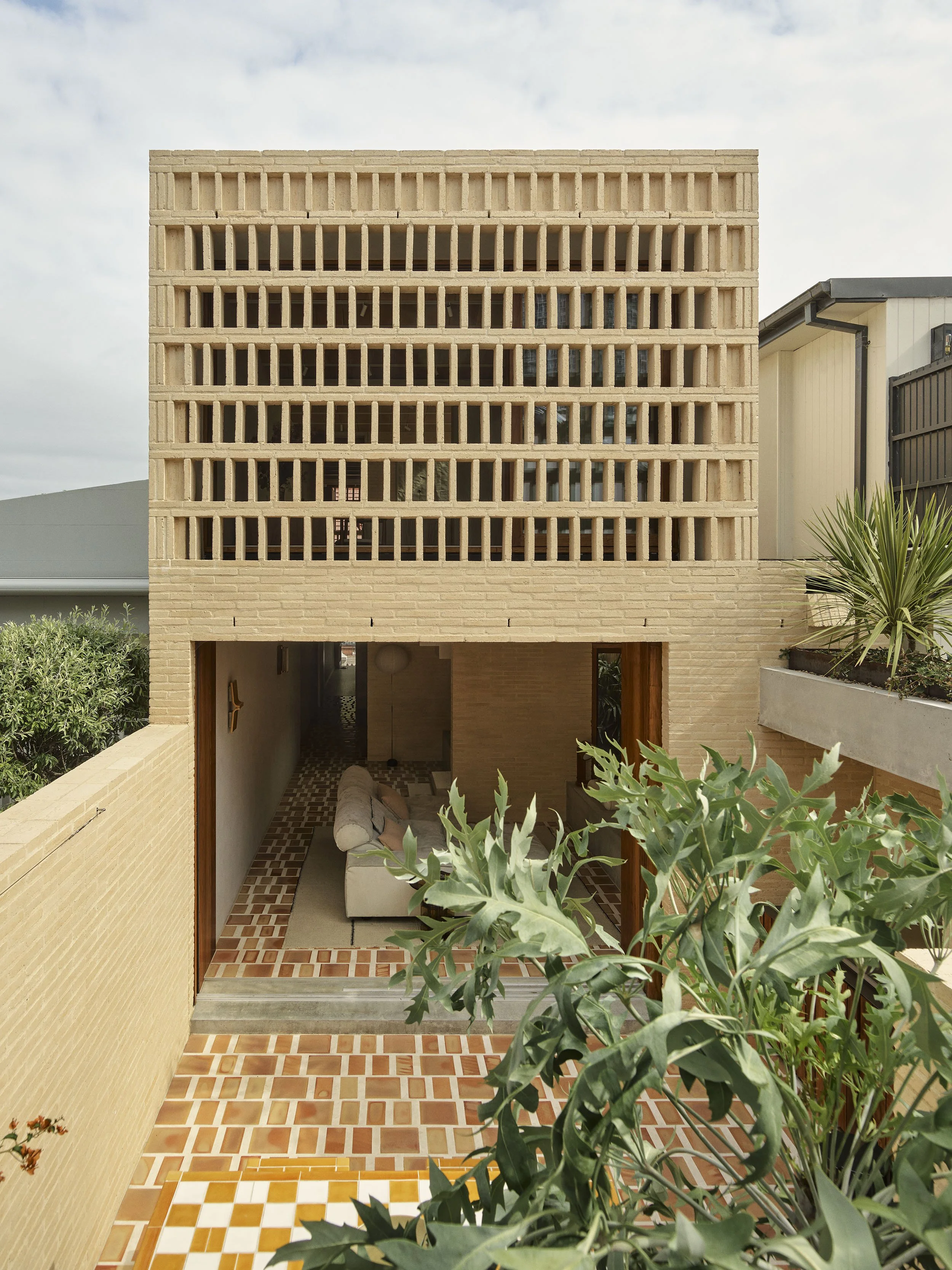 an overall photo of the rear facade of Sydney terrace renovation by muci architects. The cream brick screens completely conceal the upper level windows and the courtyard below is terracotta tiles with max-grout.