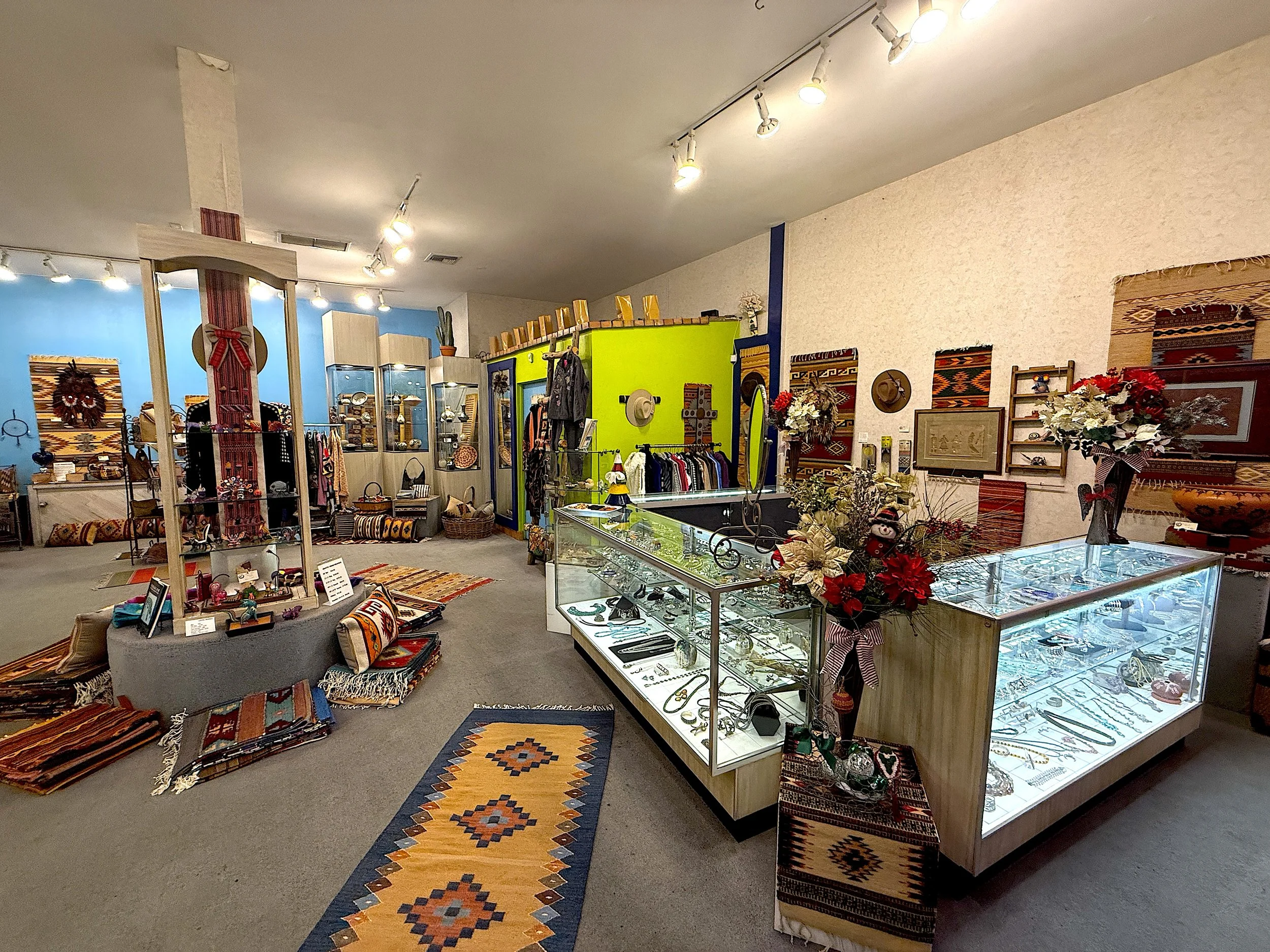 Interior of a gift shop with display cases of jewelry, collection of rugs on the floor, and decorative textiles on the walls.