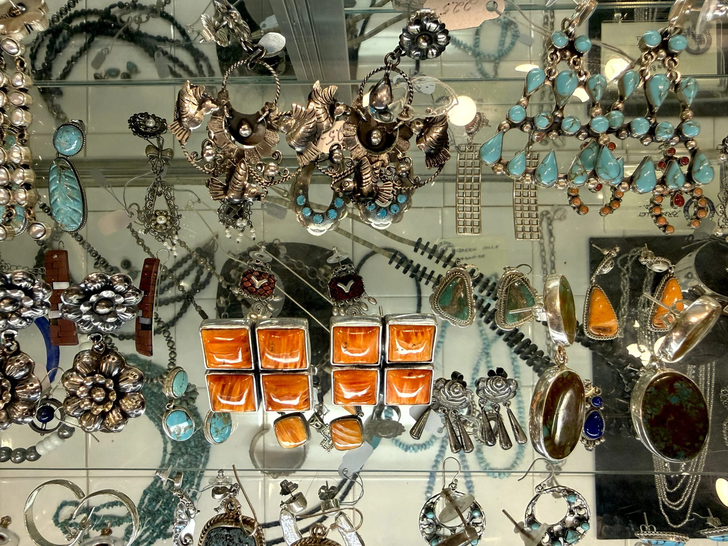 Assorted jewelry including turquoise, coral, and silver pieces, necklaces, earrings, bracelets, and rings.