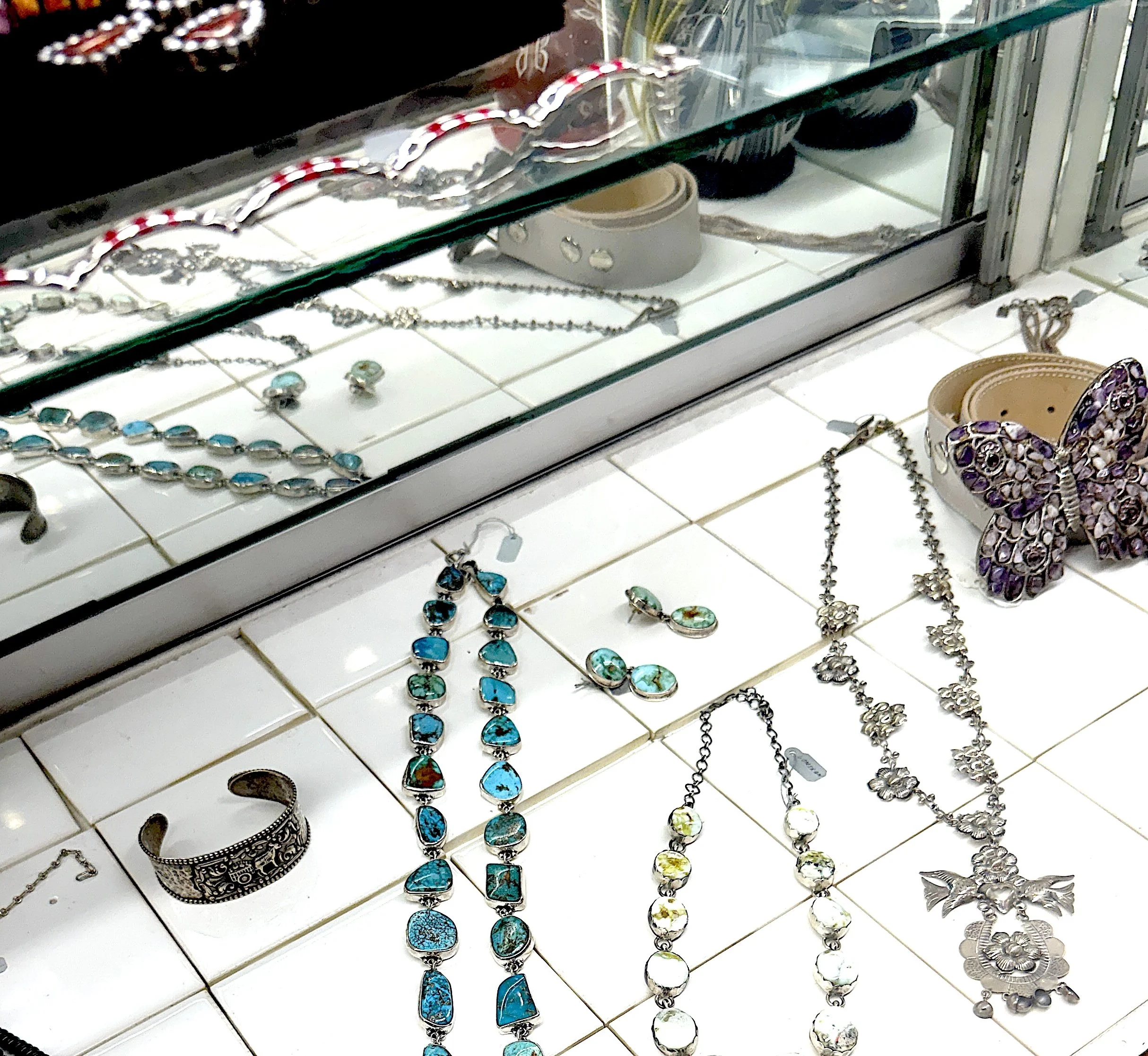 Display of jewelry including necklaces, earrings, and a butterfly-shaped bracelet.