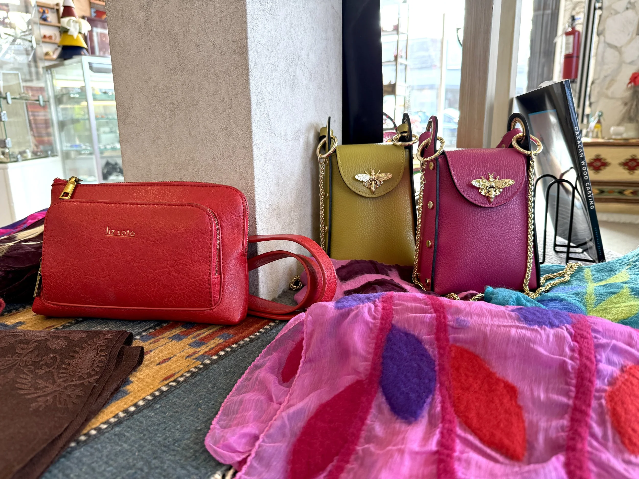 Colorful, fashionable handbags and wallets displayed on authentic handmade rugs.