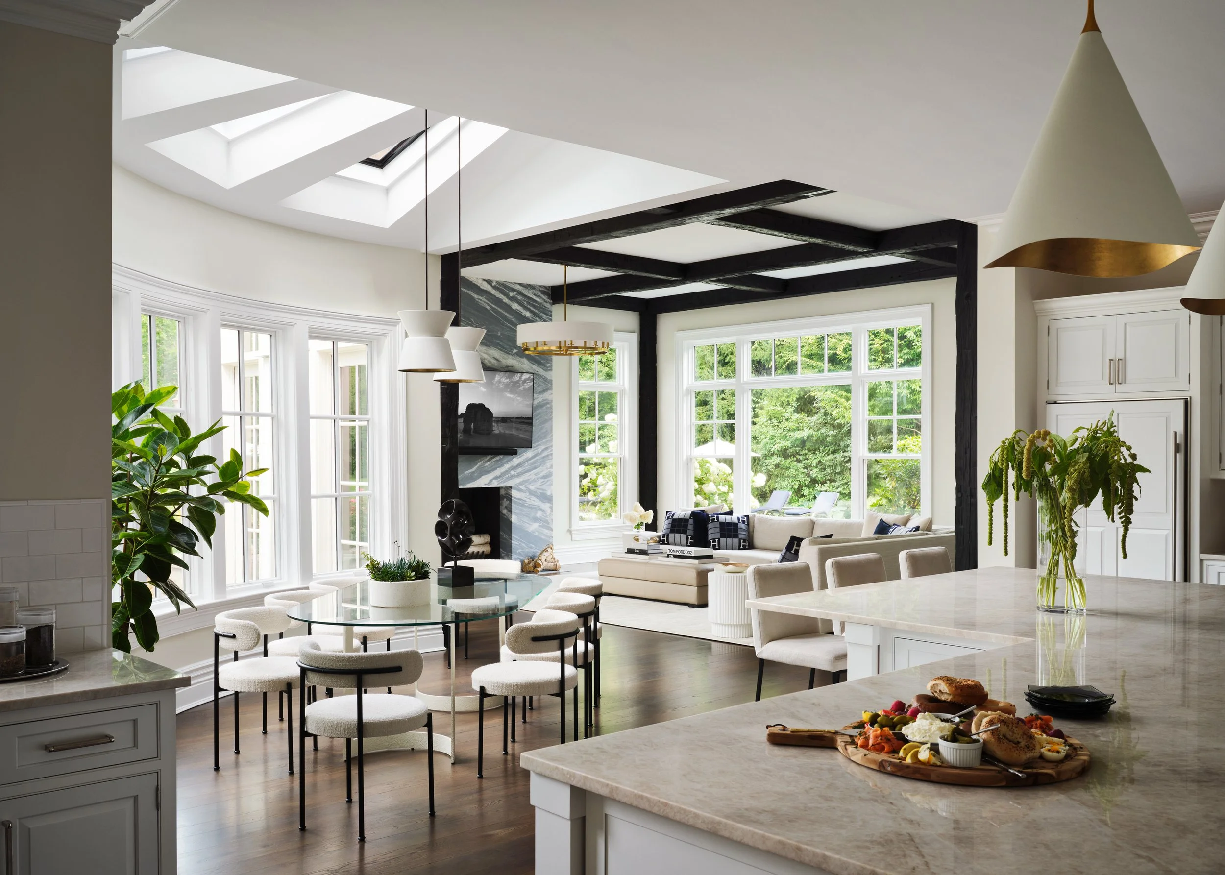 An open kitchen and great room with custom millwork, exposed beams, and a stone island in a Connecticut residence by Michele Bitter Designs