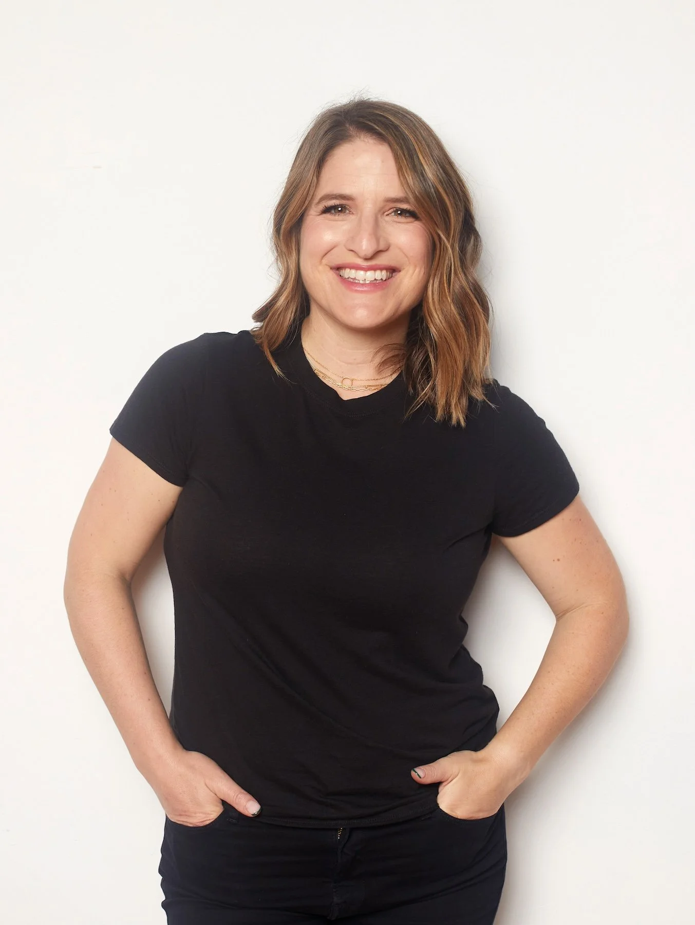 A portrait of Stacy Berger wearing a black shirt and standing against a white wall