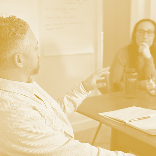Photo of a man and woman in conversation at a conference table
