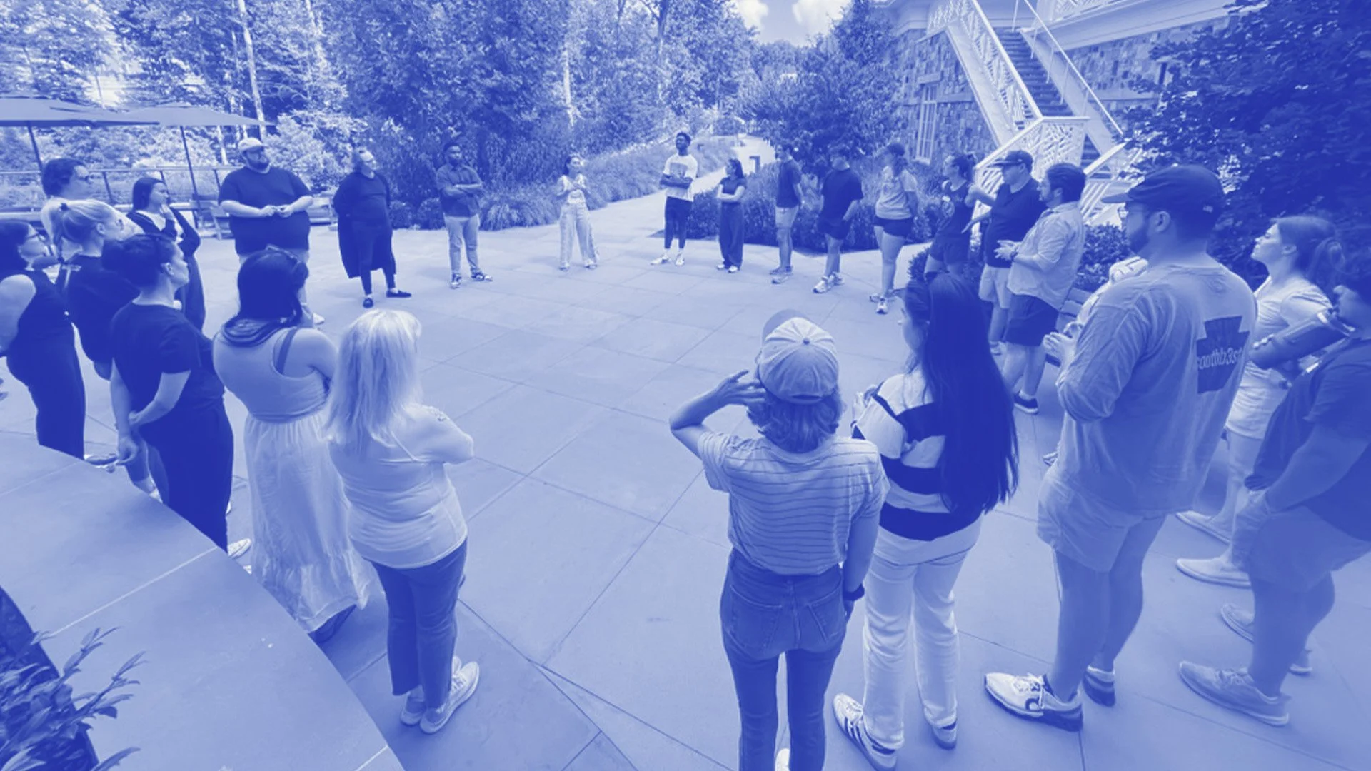 A large group of people standing in a circle outside on a concrete patio