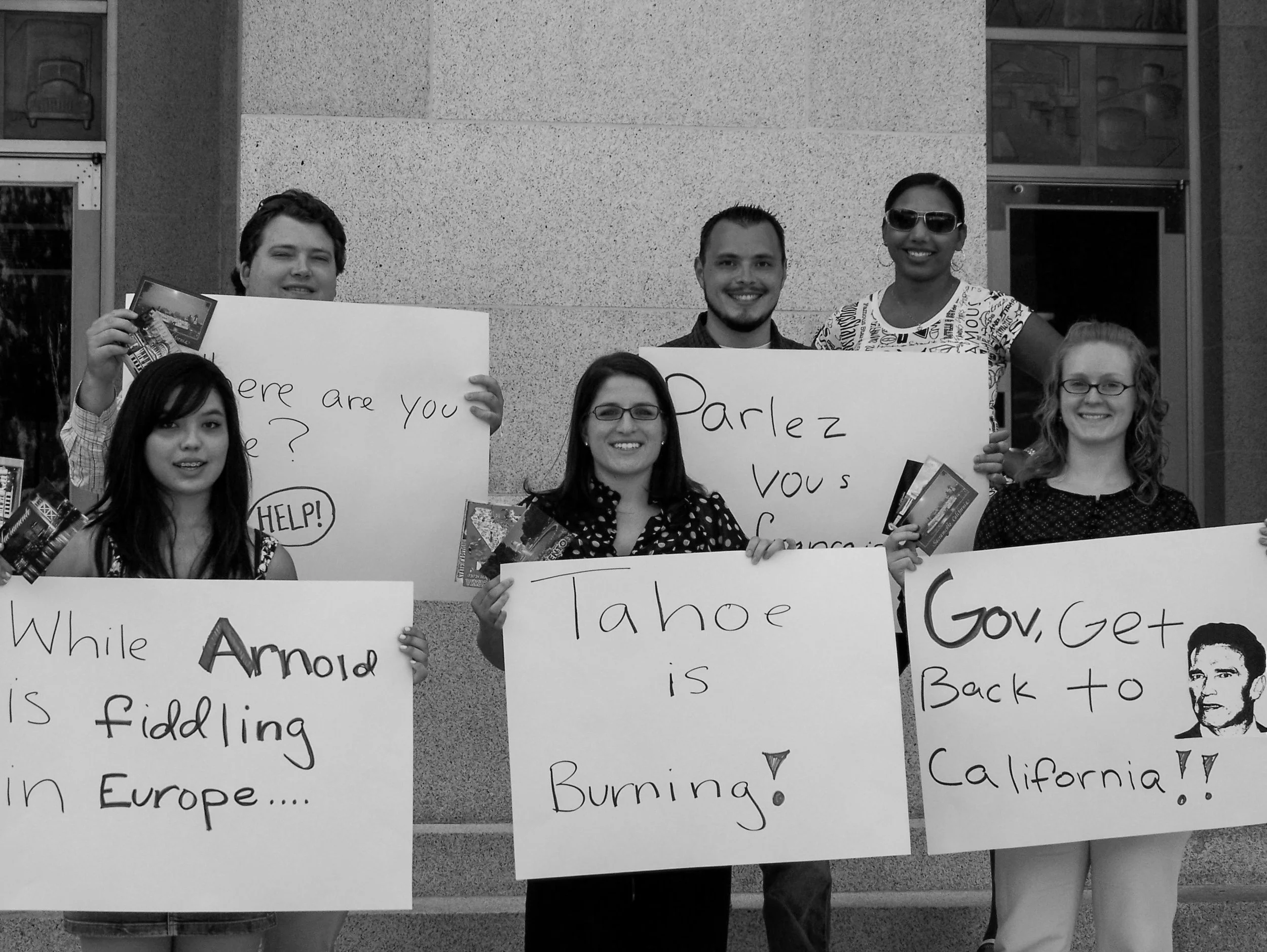 Stacy Berger stands with a group of protesters holding poster-board signs calling on the governor to return to California during the wildfires.