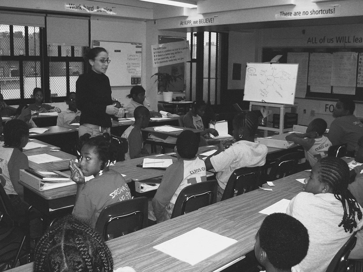 Jenna Shapiro teaching in a classroom, while students sit at desks listening and taking notes