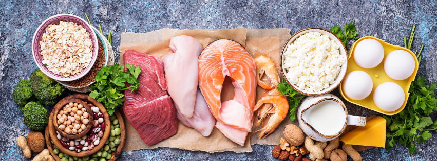 Protein foods displayed on a bench. Eggd, meat, fish, seafood, nuts, seeds, lentils, edamame and milk.