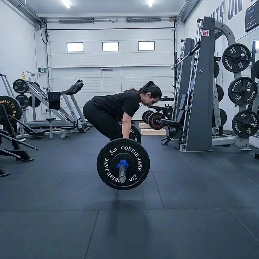 Women in black strength training doing an romanian deadlift in a gym