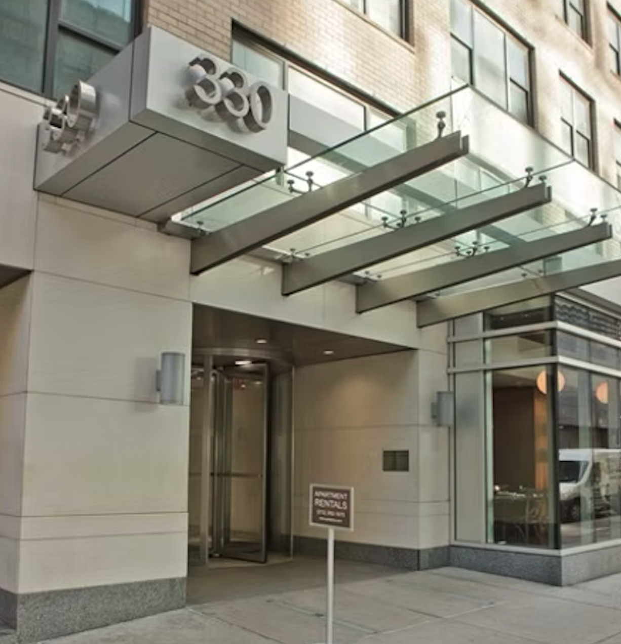 Modern building entrance with the address number 350 displayed above the door and an apartment rentals sign outside.