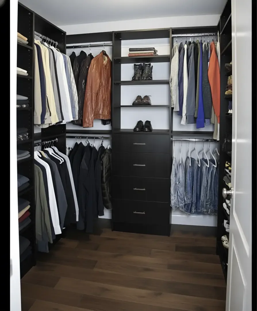 Organized walk-in closet with black shelving, hanging clothes, folded clothes, shoes on shelves, and a drawer unit in the center.