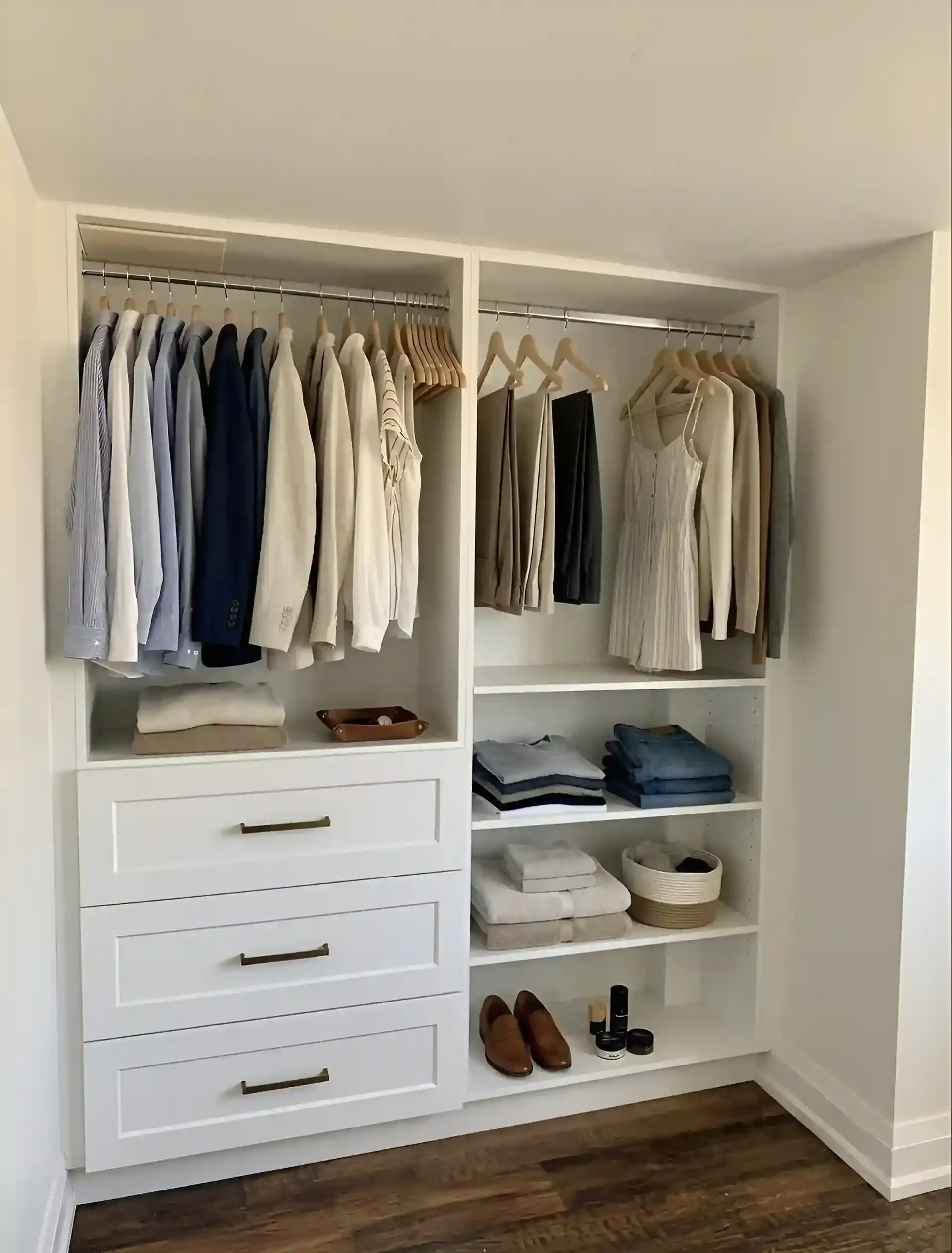 A white closet with hanging clothes, folded towels, shoes, and small personal items on shelves.