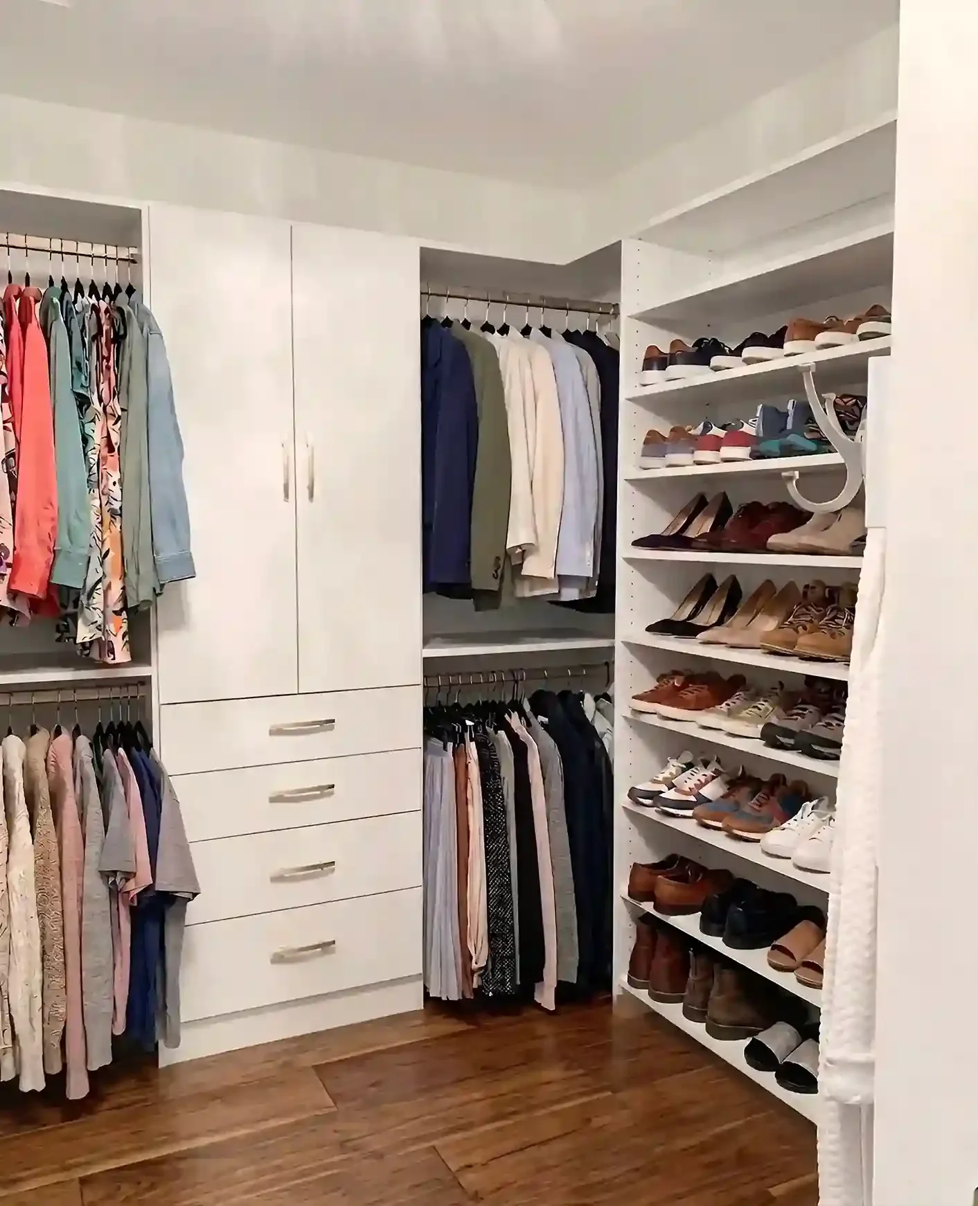A walk-in closet with clothes hanging on racks, shelves with shoes, and drawers for storage.