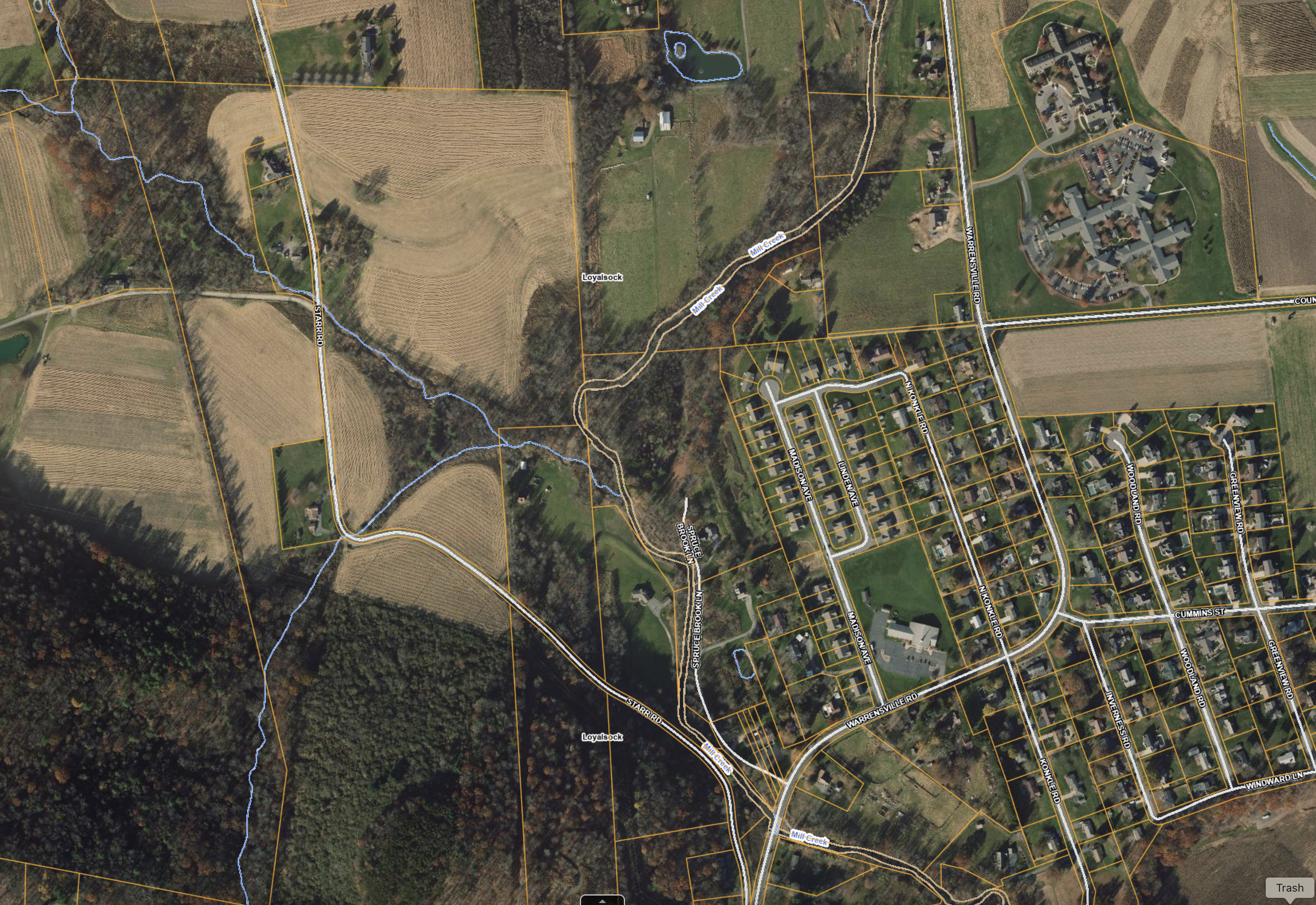 Aerial view of a suburban area with roads, residential homes, farmland, and a creek, with labels of street names and property boundaries.