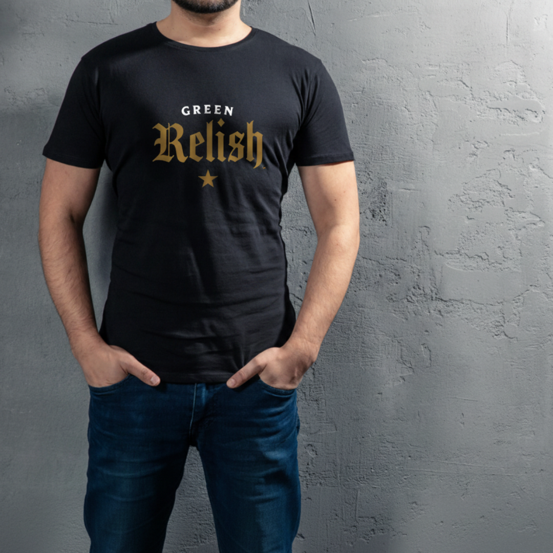 A man wearing a black T-shirt with the words 'Green Relish' printed in gold and white letters, standing against a textured gray wall.