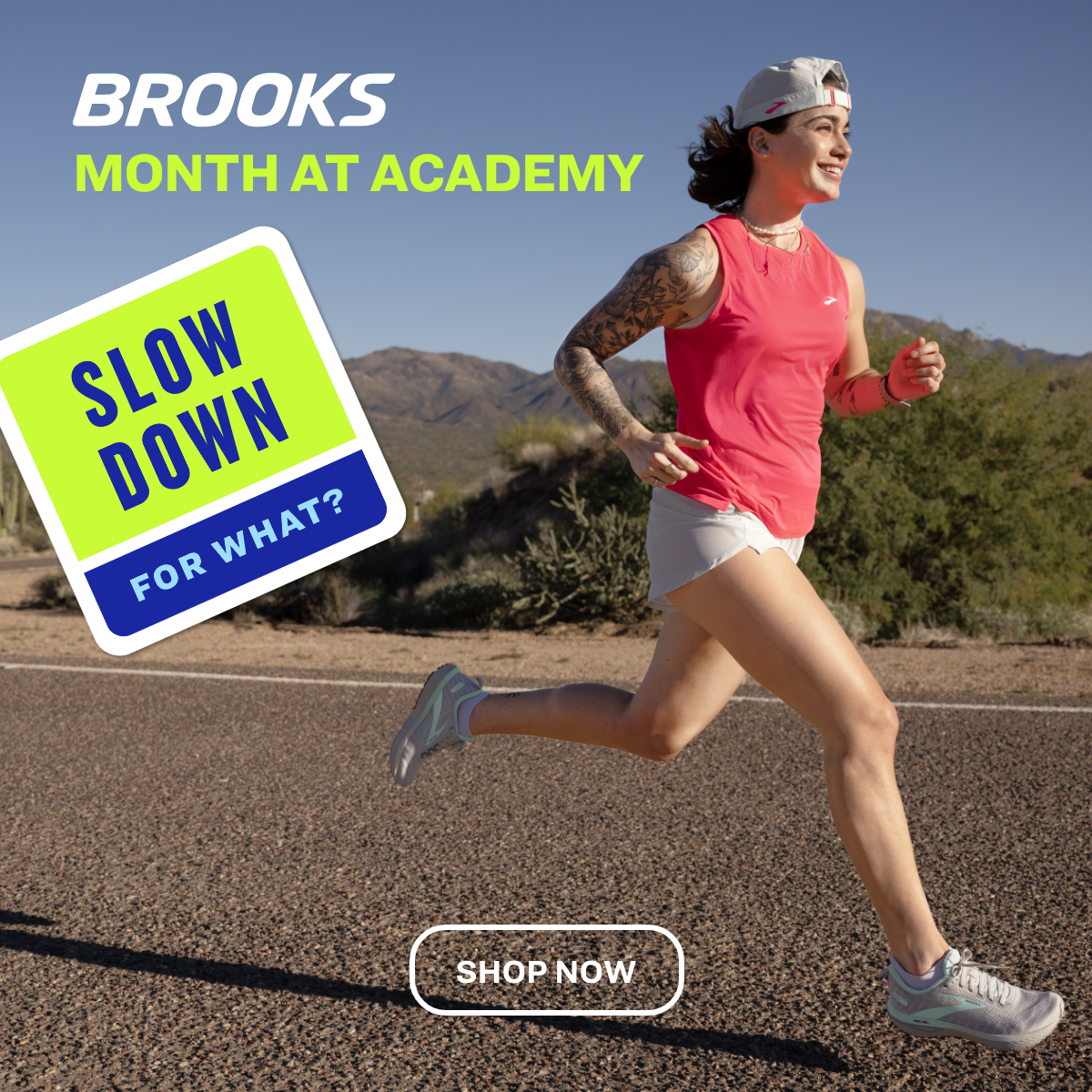 A woman running outdoors in a pink tank top, white shorts, and running shoes, with desert mountains in the background. Text overlay says 'Brooks Month at Academy' and 'Slow Down for What?'. Button says 'Shop Now'.